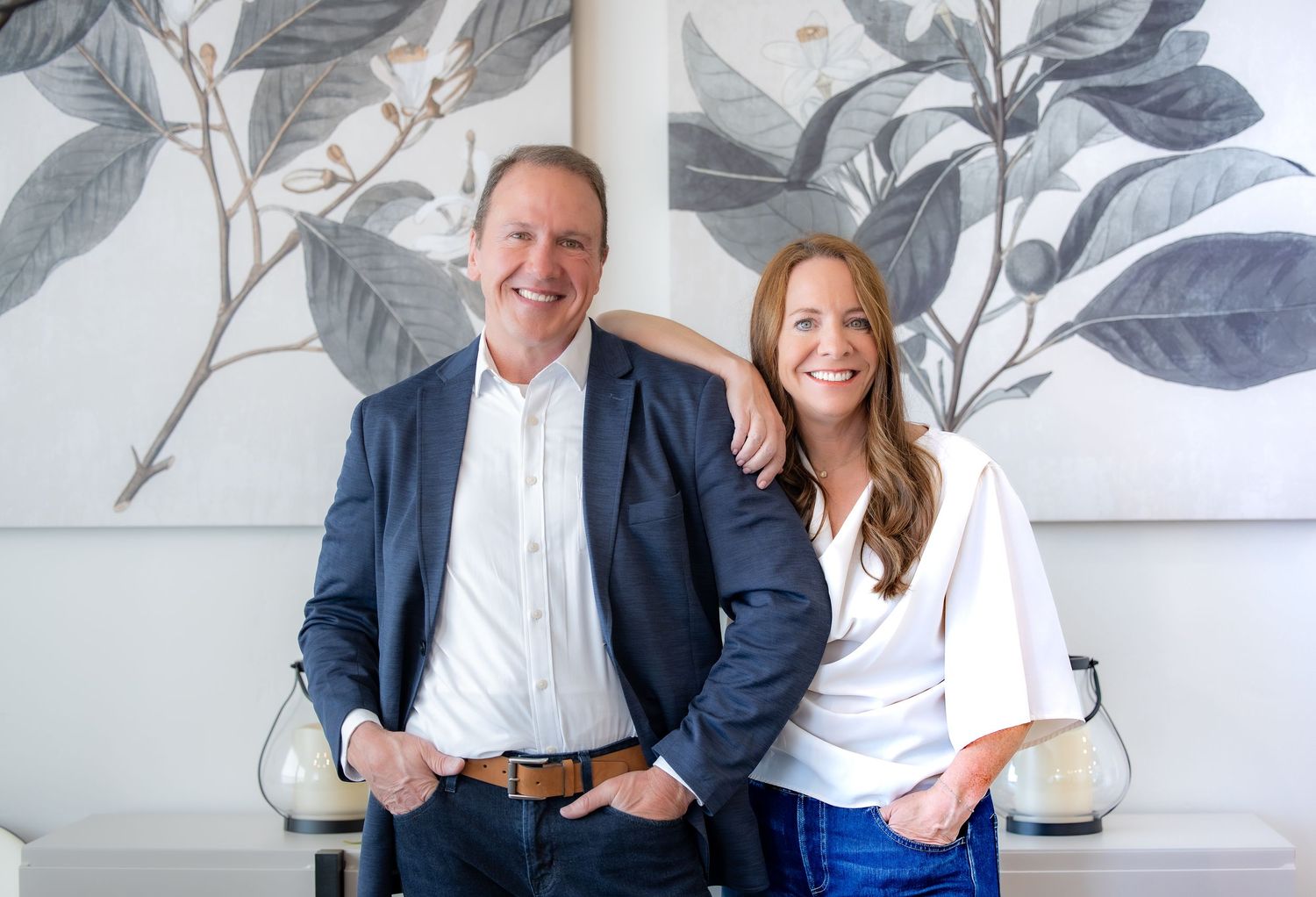 Professional business partners pose together in an office with a modern botanical wall mural backdrop.