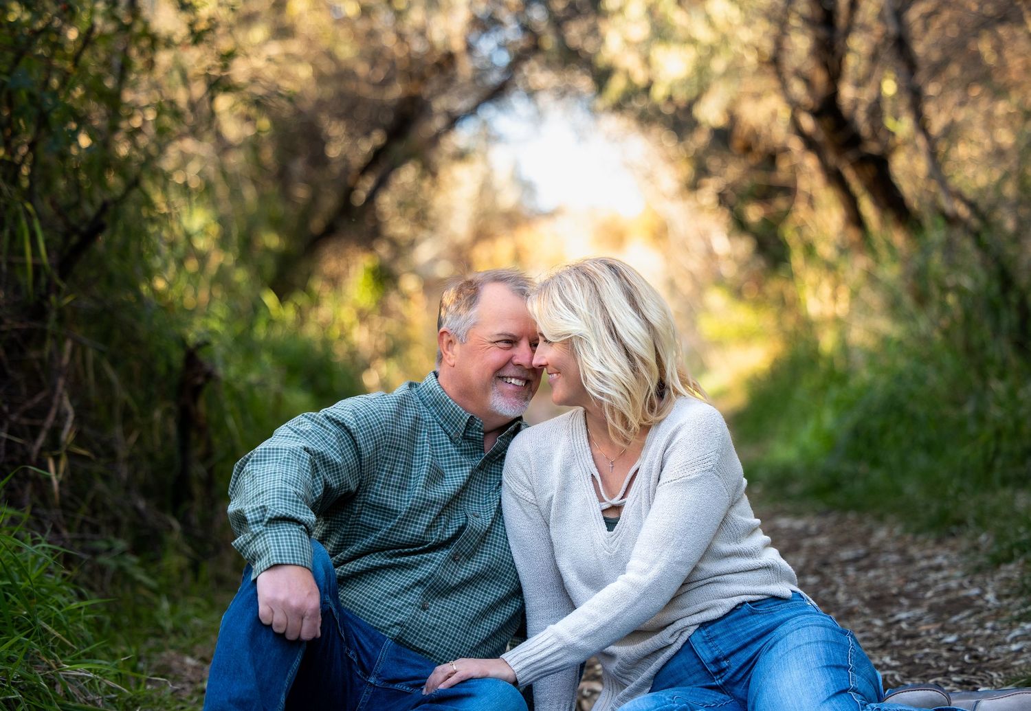 A couple shares tender moments together in a wooded outdoor setting during a golden sunset photoshoot.