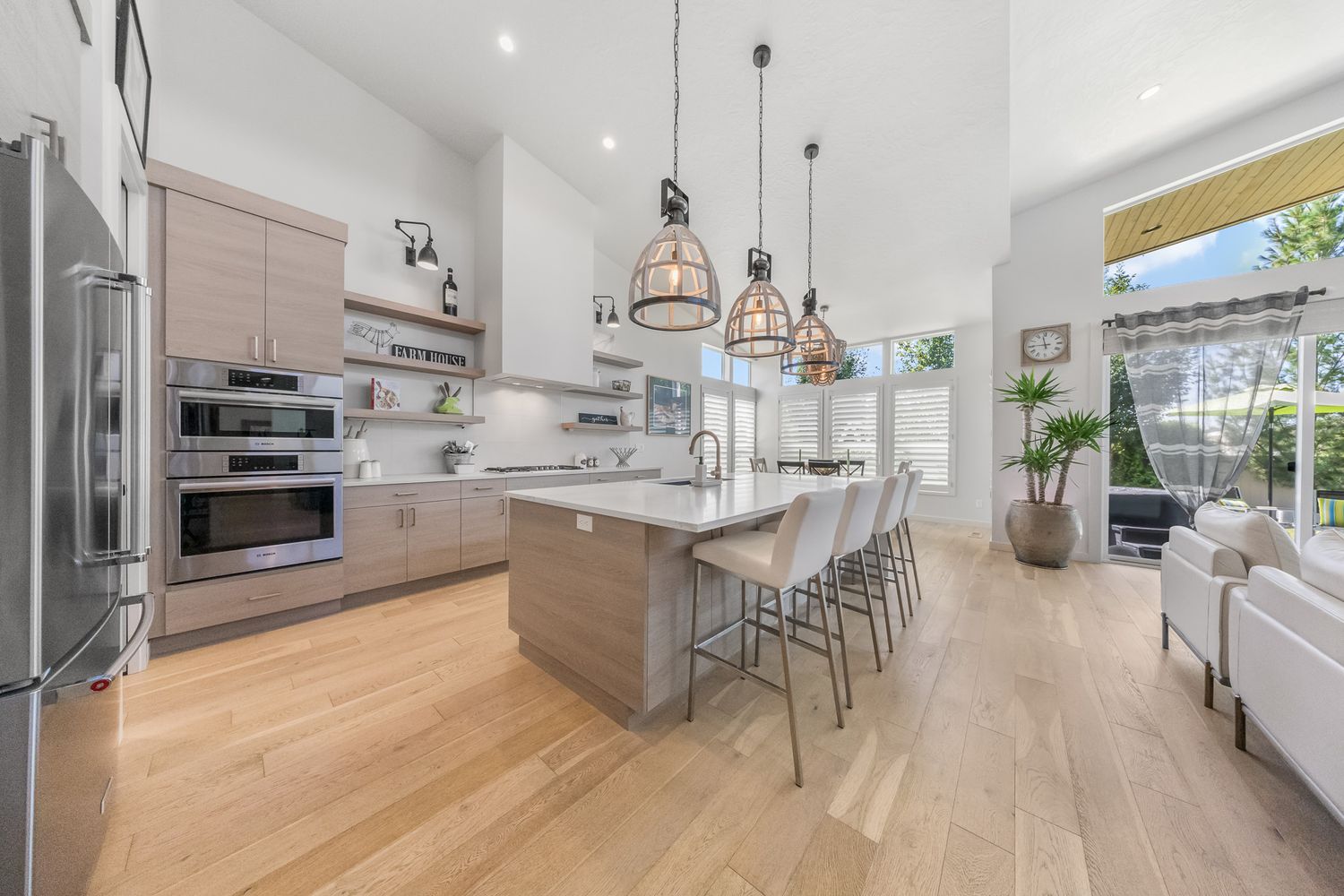 Modern open concept luxury apartment interior with white walls, light wood floors and pendant lighting over kitchen island.