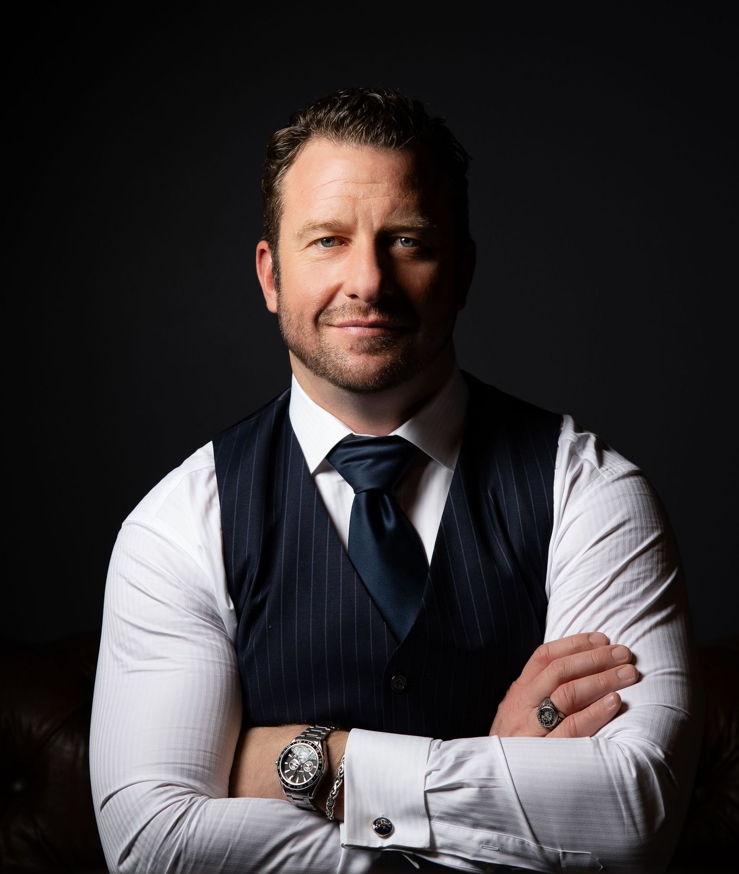 Professional studio portrait series showing a person in a navy pinstripe vest and white dress shirt against dark background.