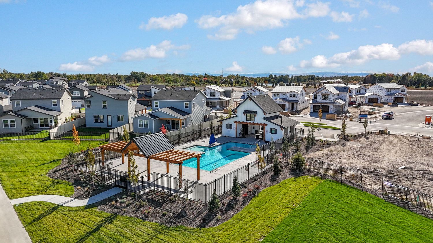Panoramic aerial view of waterfront properties and docks along a coastal community under blue skies.
