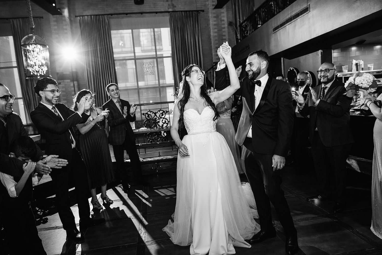 A joyous wedding celebration moment in black and white as couple raises joined hands triumphantly on the dance floor. Restaurant Le Richmond