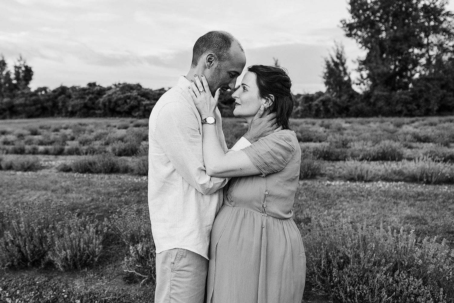 Black and white photo of a romantic couple embracing in a lavender field at sunset.