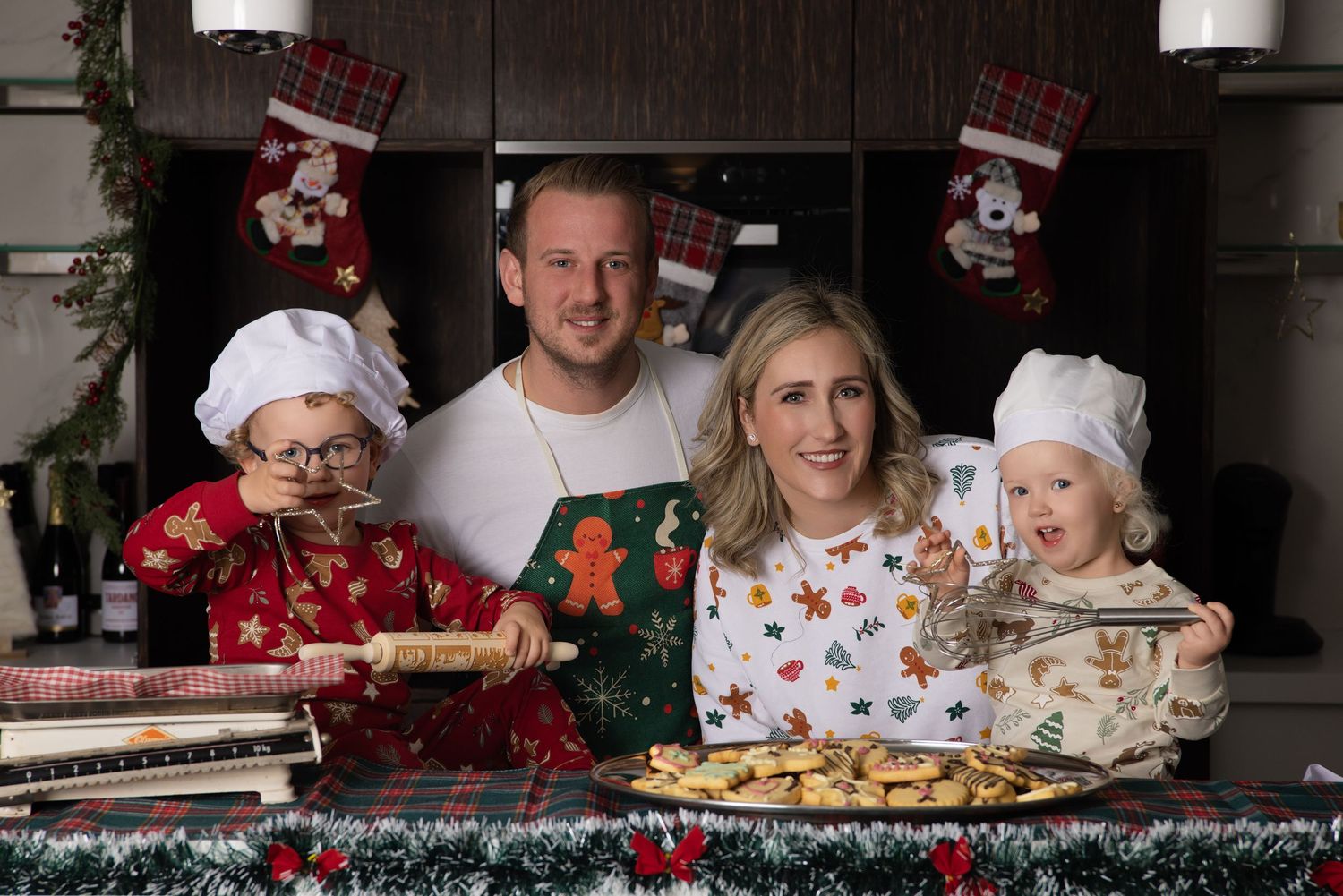 Family members decorating Christmas cookies with frosting and sprinkles on a kitchen counter during holiday baking.
