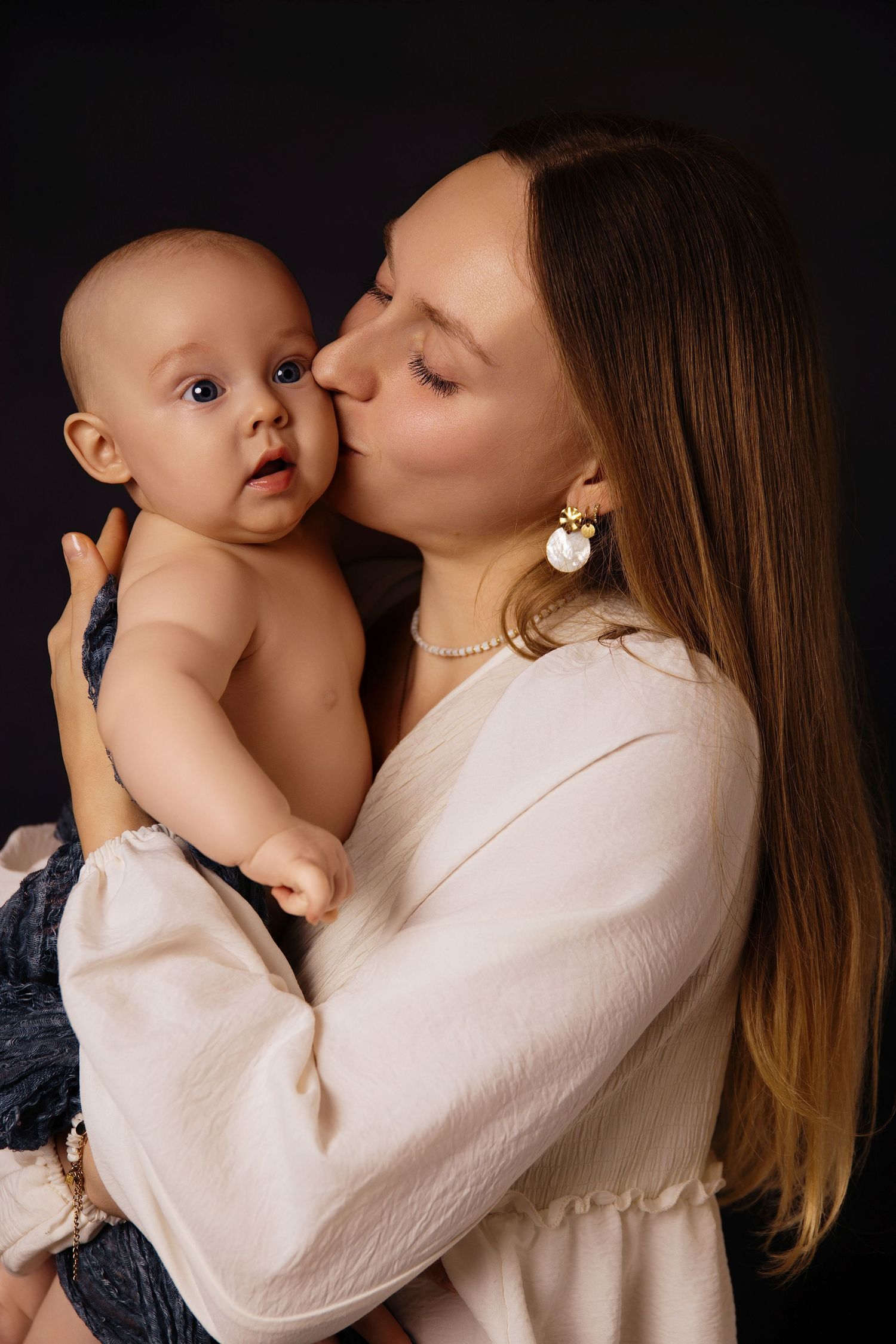 A tender moment captured in a series of intimate photos showing a parent in white embracing and kissing a baby.