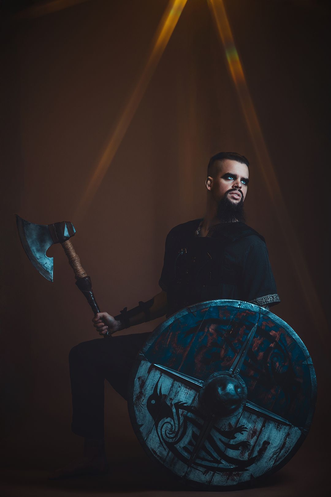 Viking warrior holding battle axe and decorated round shield, dramatic studio lighting, dark background.