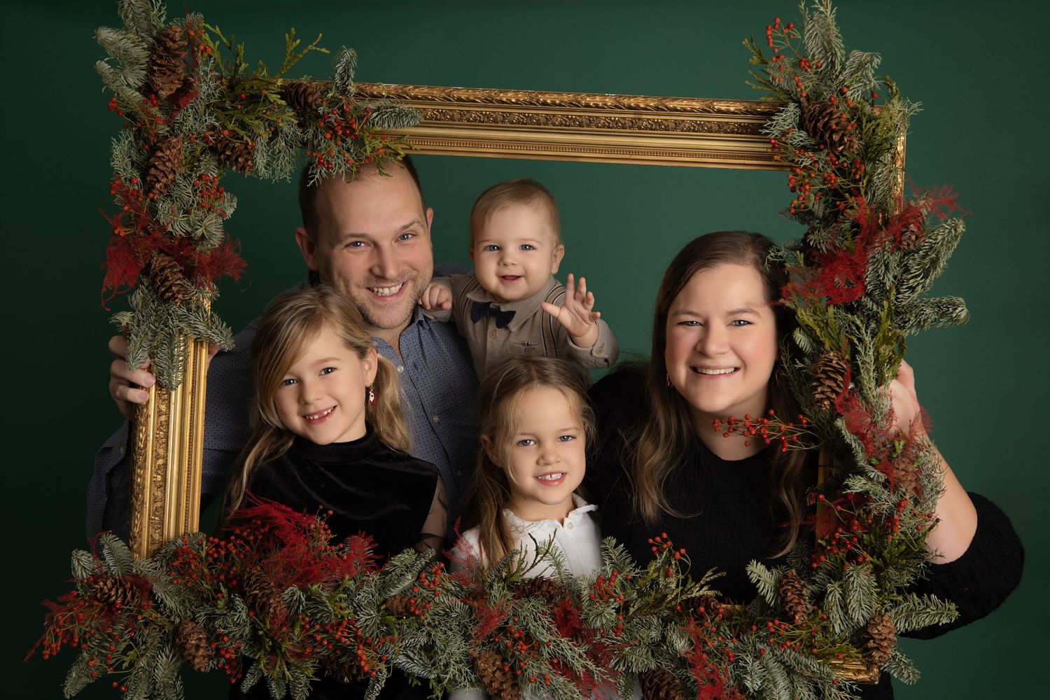 Holiday portrait series showing people posing with festive Christmas wreaths and ornate gold frames in a dark studio setting.
