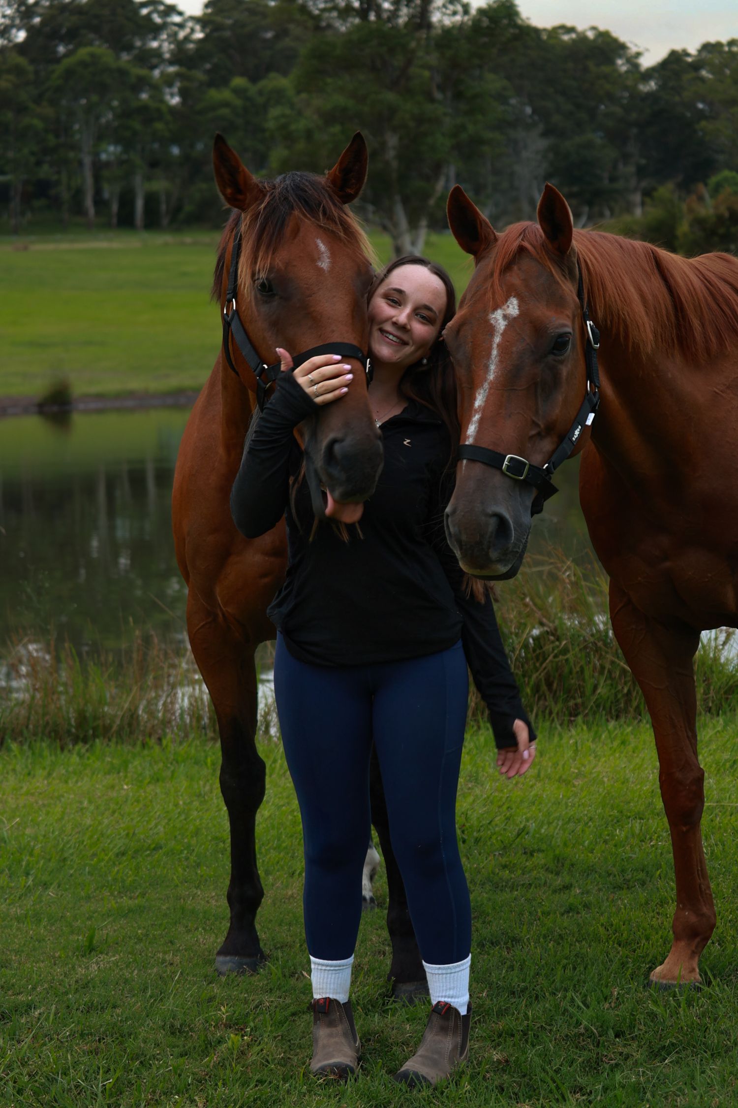 A series of progressive shots of someone posing with a horse in a grassy field by a lake.