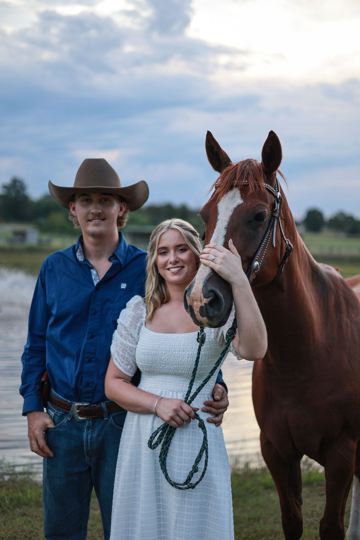 Country western photoshoot featuring a couple and their horse by a lake.