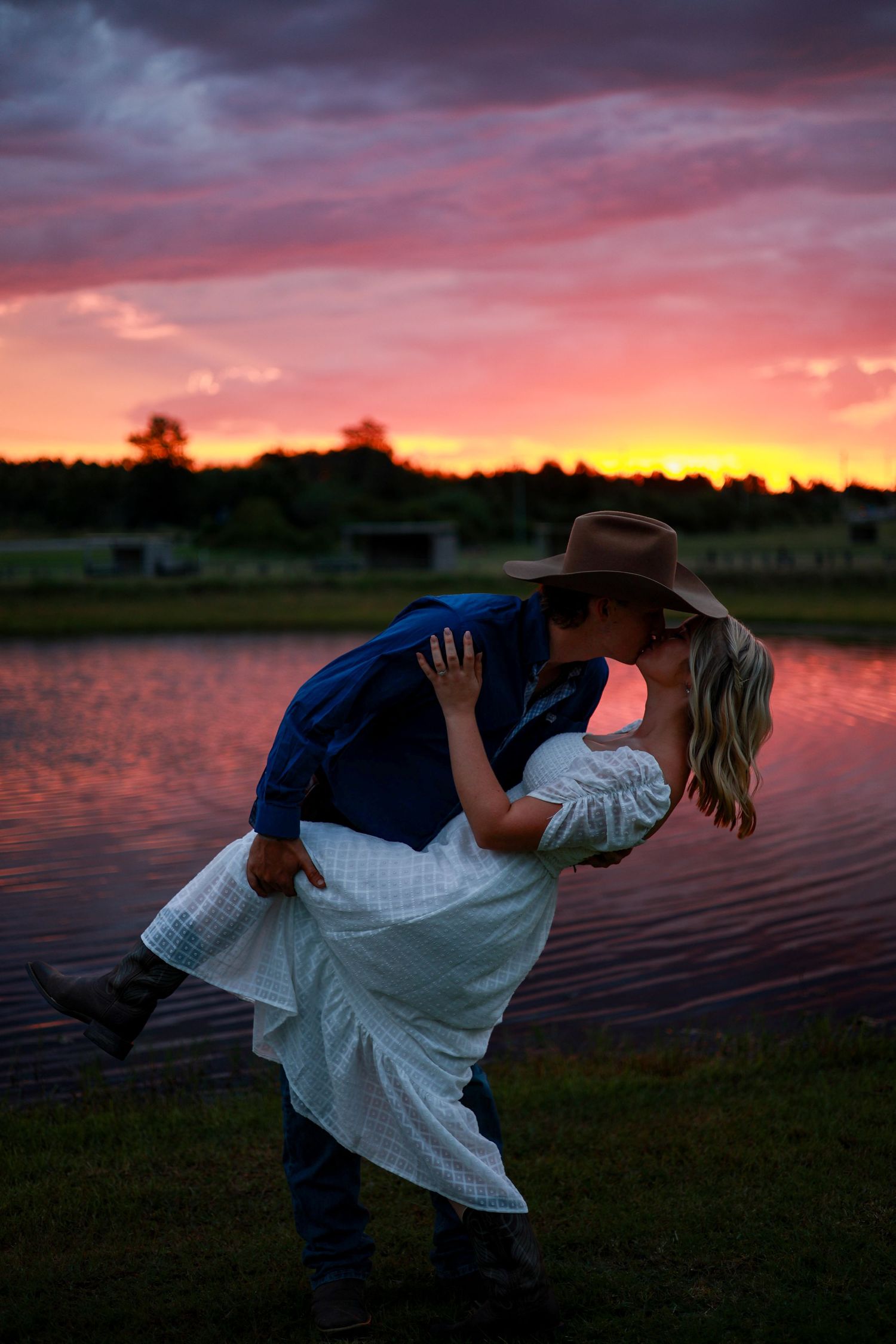 A romantic silhouette of a couple dancing by a lake at sunset with vibrant pink and orange sky.
