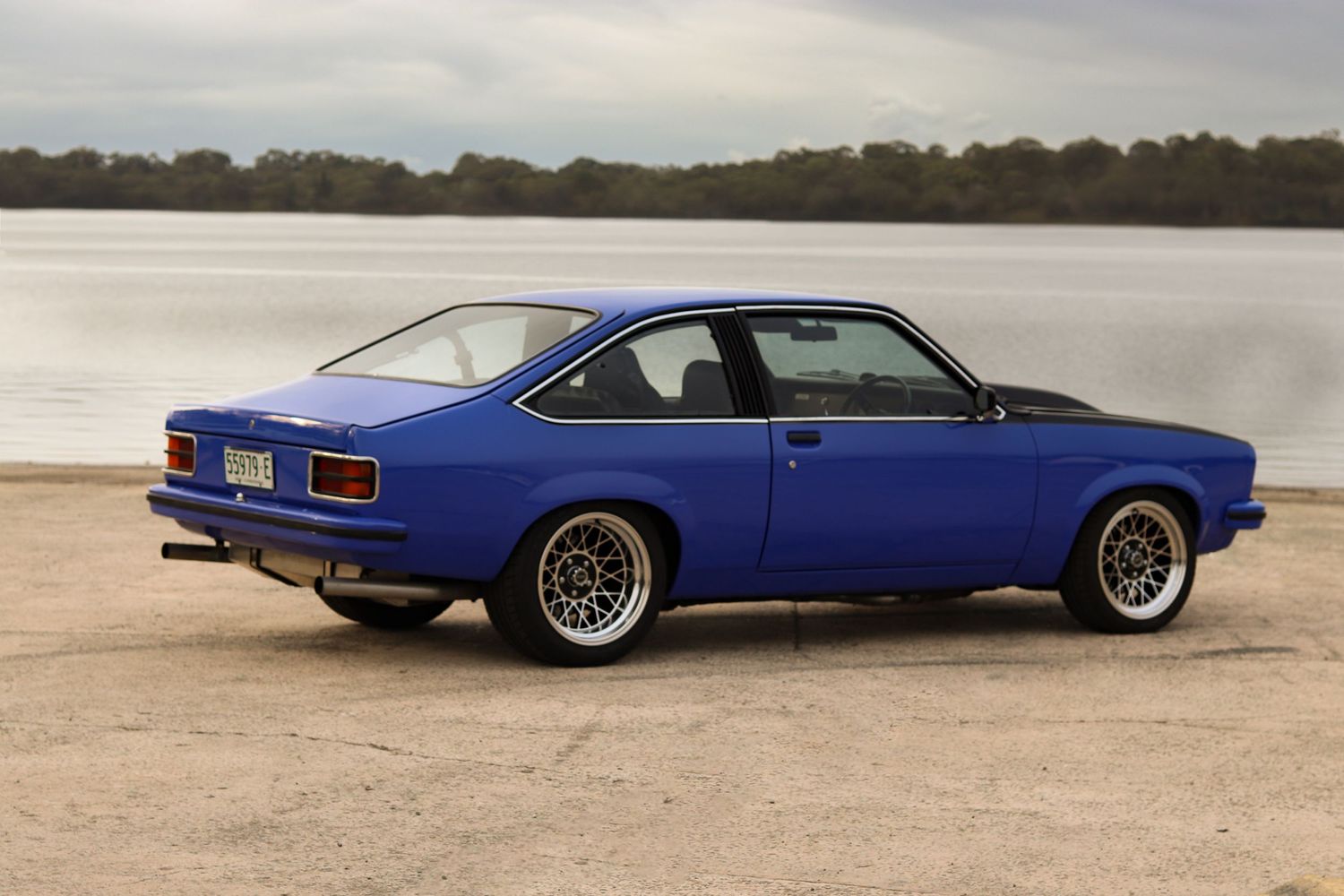 blue Torana with custom wheels shown from various angles under overcast skies.