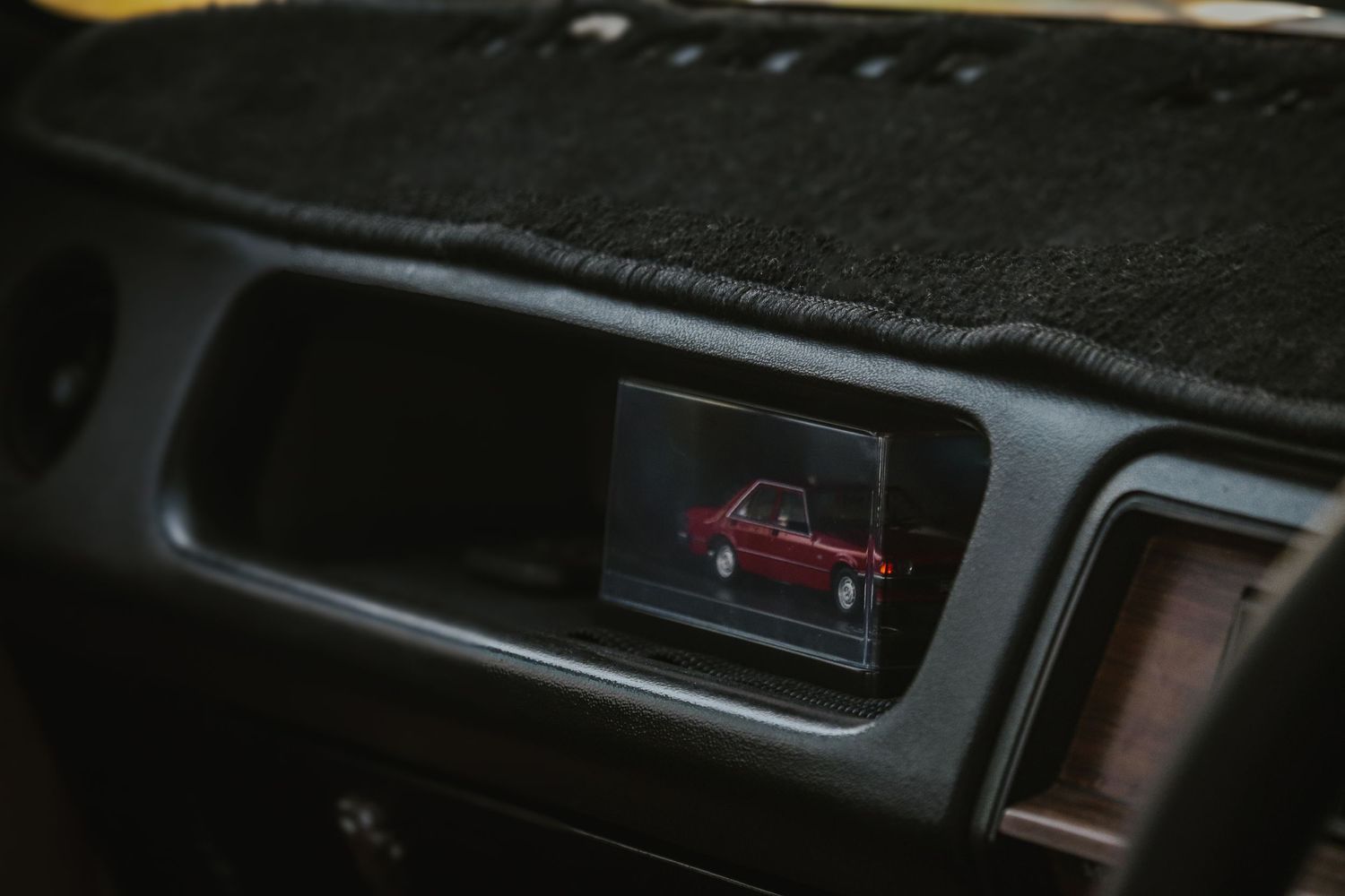 Car showing a replica small red vehicle icon against dark interior dashboard.