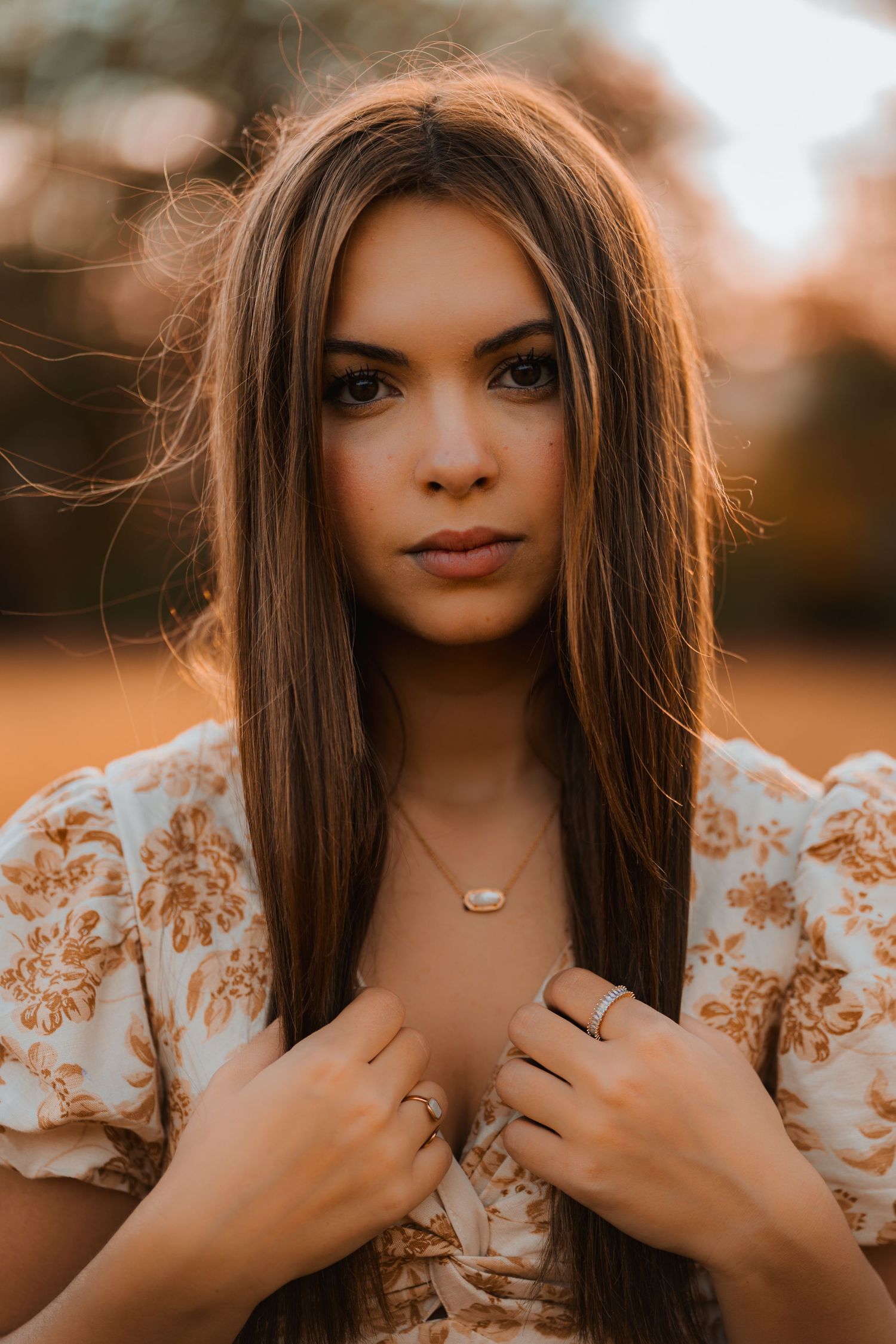Portrait of someone in a floral patterned dress with long brown hair during golden hour sunset lighting.