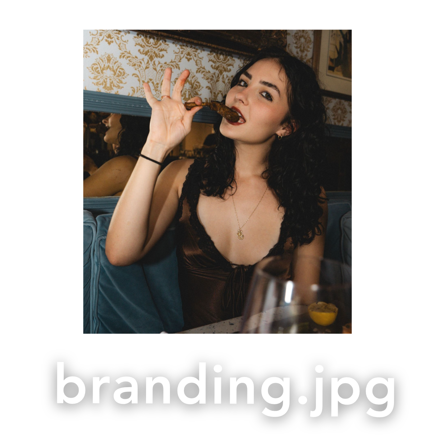 Young woman with dark curly hair enjoying a meal at a stylish restaurant, holding food to her lips.