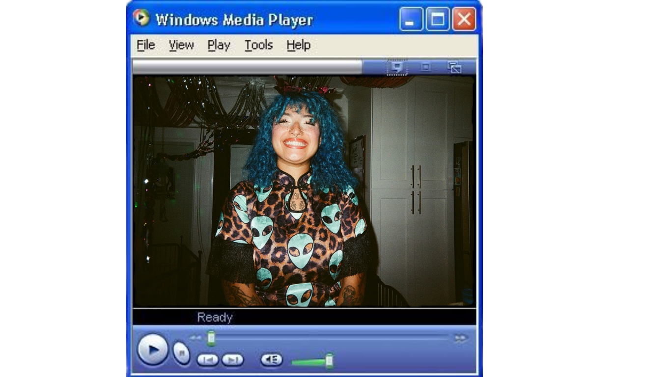 Woman with blue hair smiling in a leopard print shirt, displayed in Windows Media Player on a Windows XP desktop.
