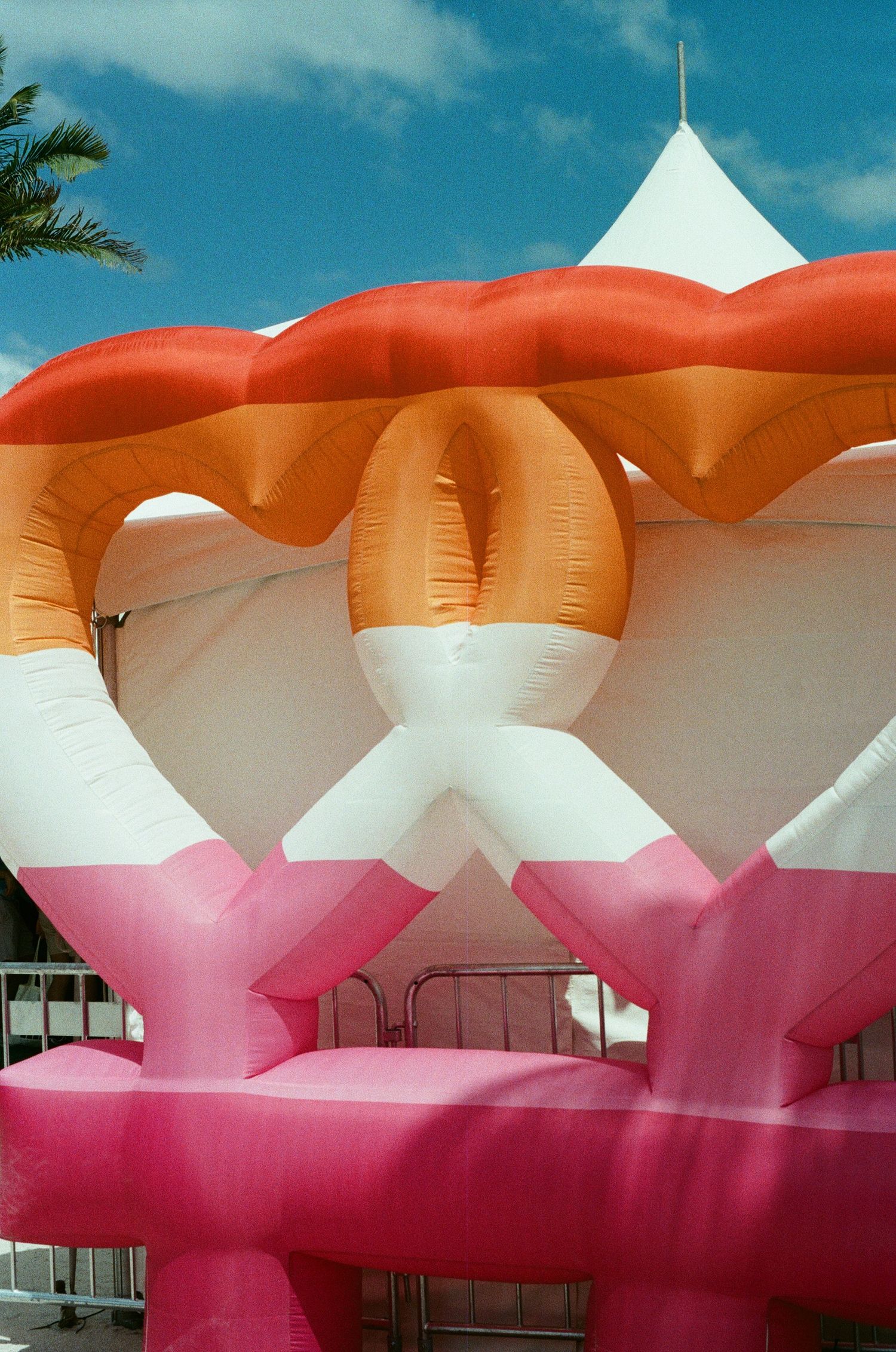 Colorful inflatable art installation in pink, orange, and white abstract shapes against a blue sky.