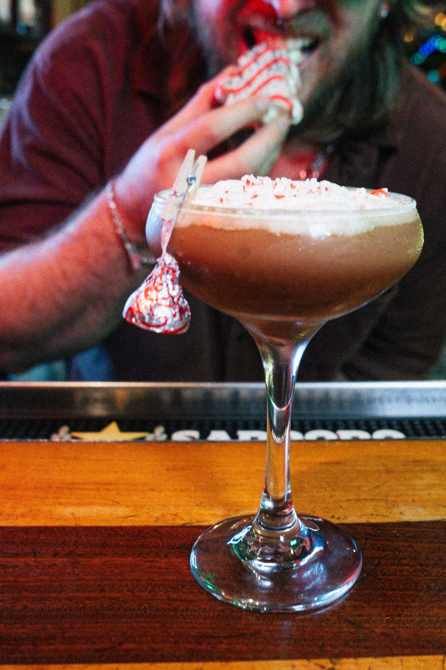 A creamy chocolate peppermint cocktail topped with whipped cream and candy cane pieces in an elegant coupe glass.
