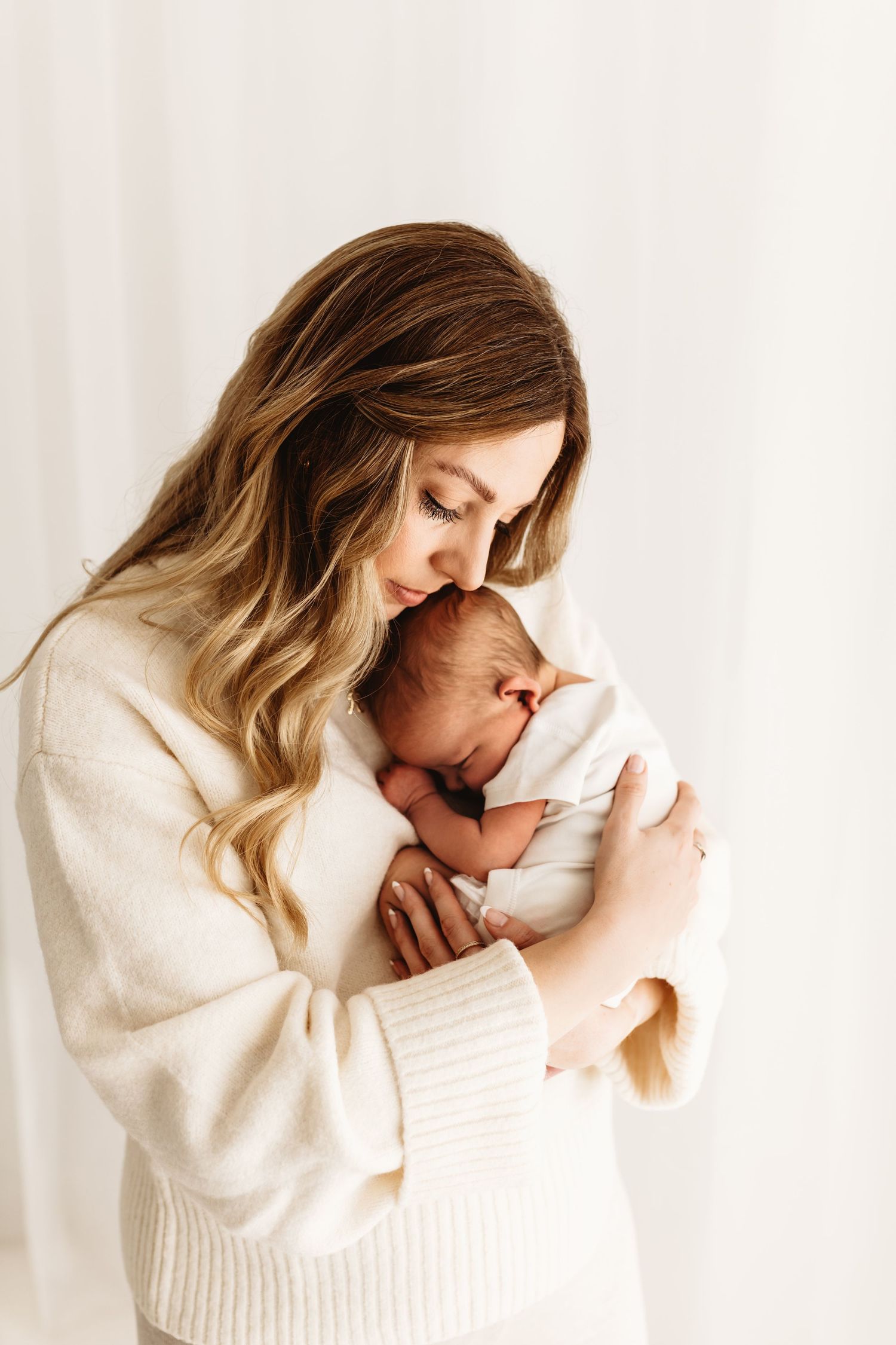 A new mum hugging her newborn baby during a newborn photoshoot in Corby, Northamptonshire