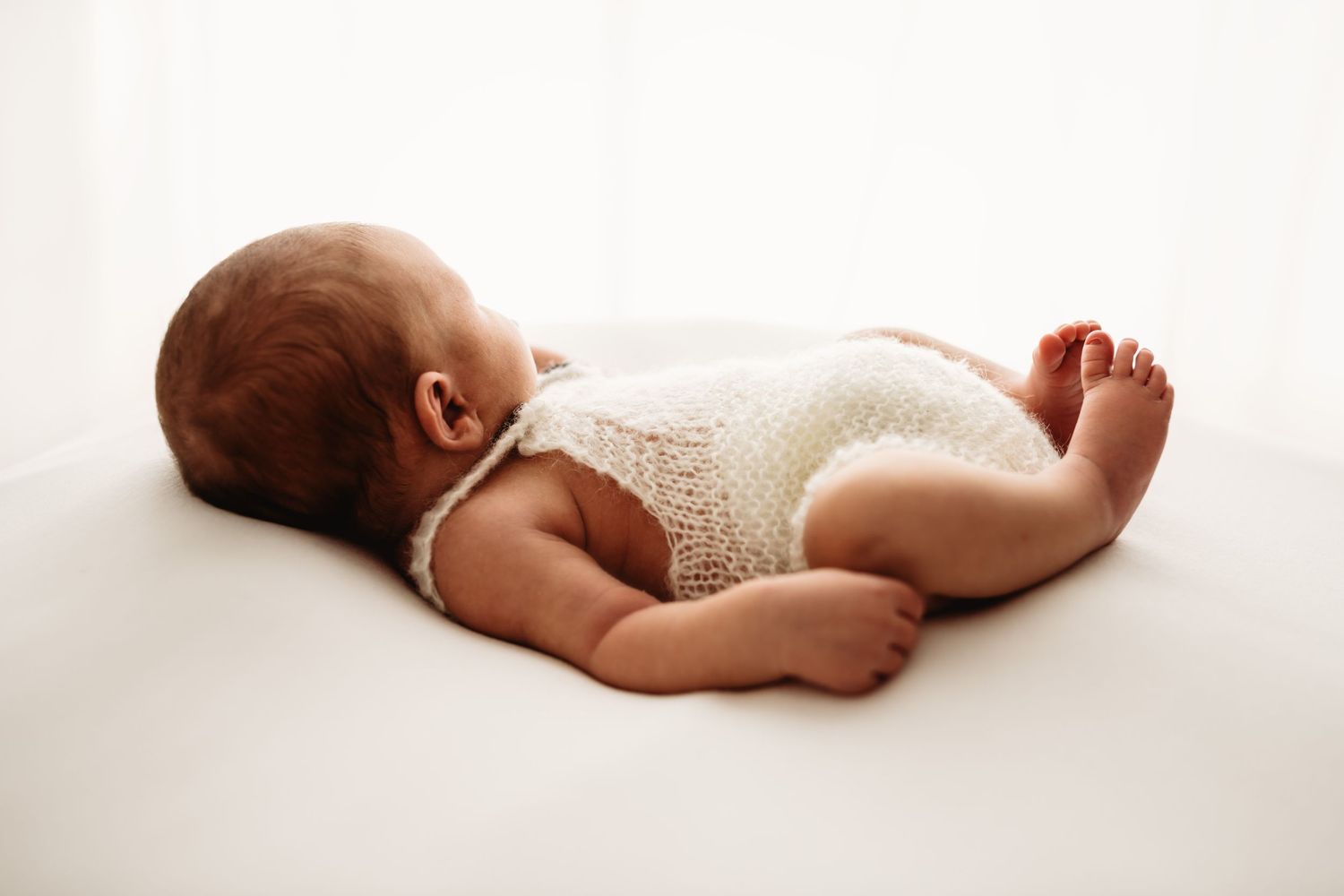 A series of five artistic black and white photographs showing a sleeping newborn baby in different poses.