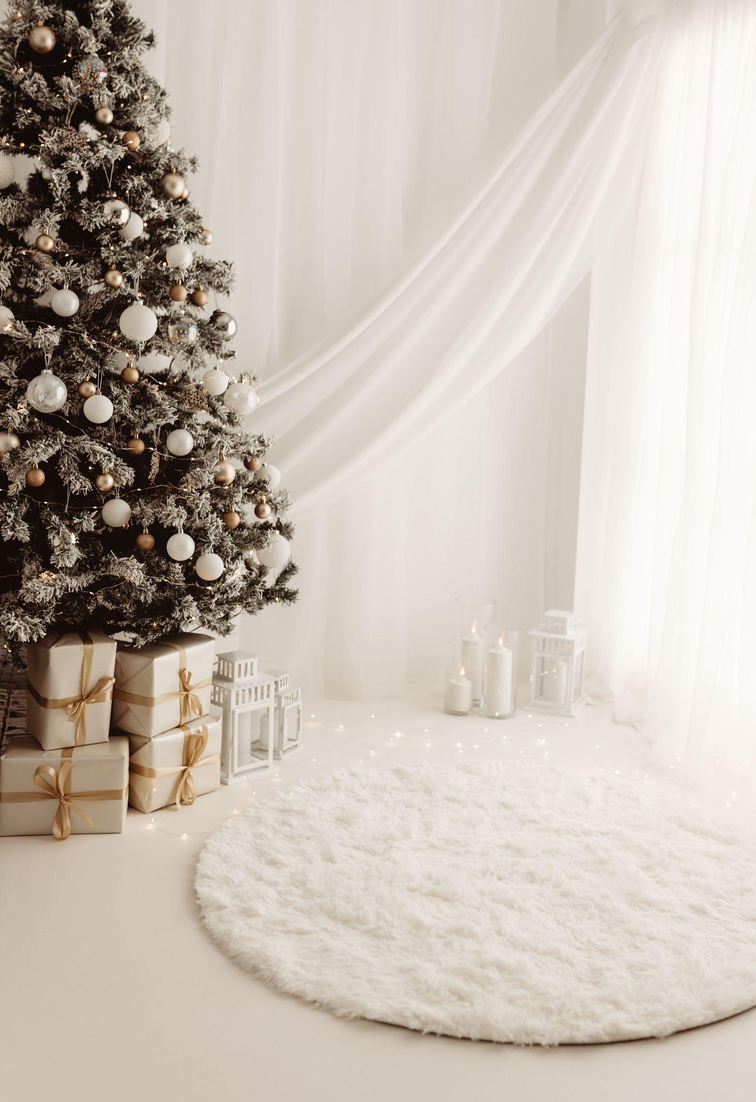 Elegant white Christmas room with frosted tree, gold-wrapped gifts, white fur rug, candles, and sheer curtains.