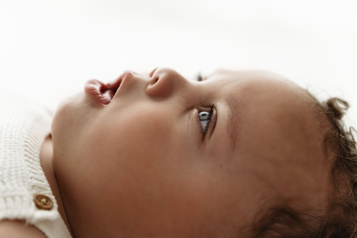 Four different profile shots of a baby lying down with different expressions and poses on a light background.