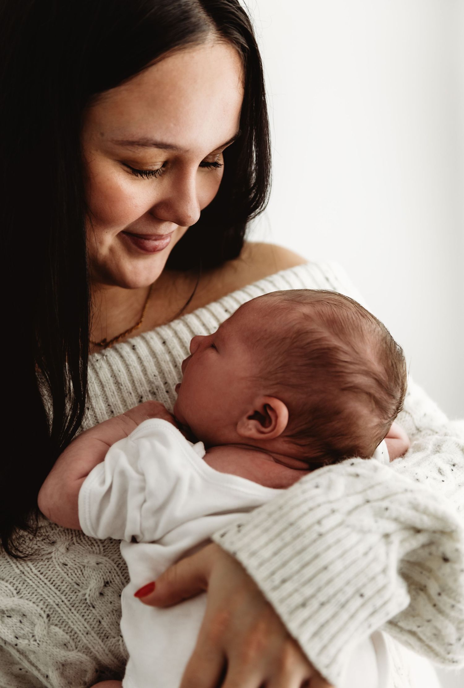 A tender moment captured in a series of photos showing a parent in a white sweater cradling a newborn baby.