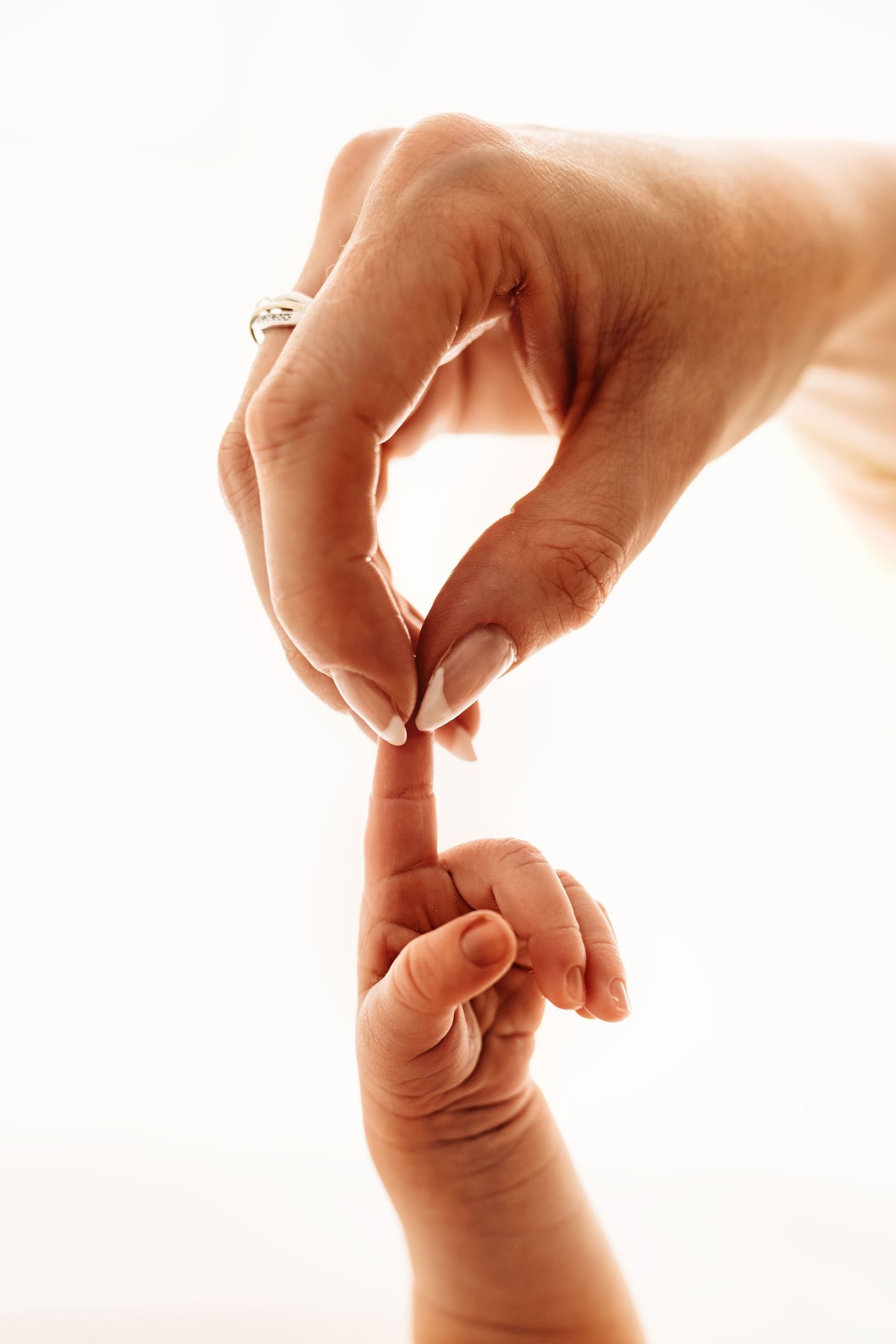 A baby's hand gently gripping an adult's finger, symbolizing the bond between parent and child.