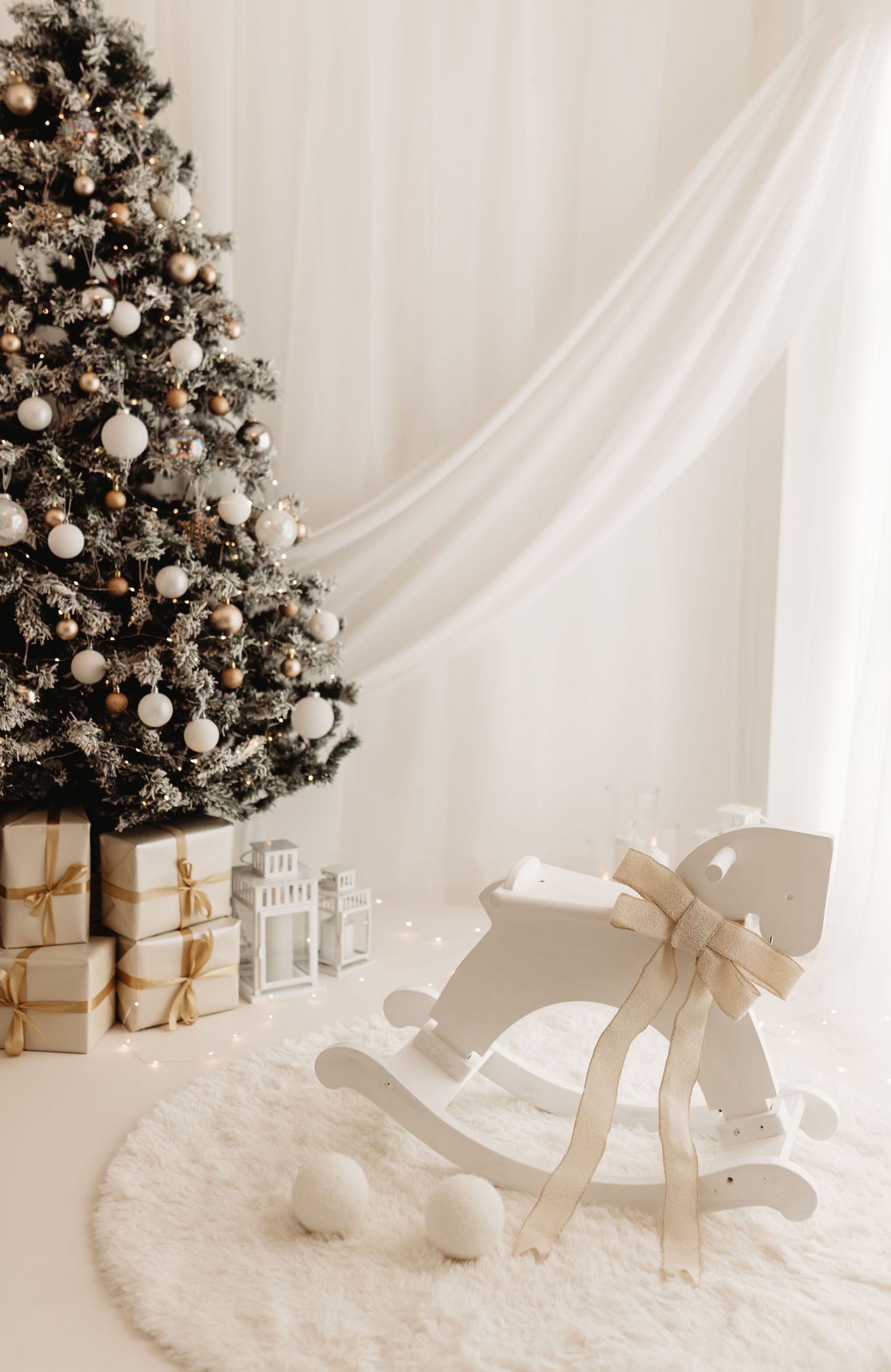 White Christmas room with decorated tree, gold gifts, rocking horse on fluffy rug, and sheer curtains.