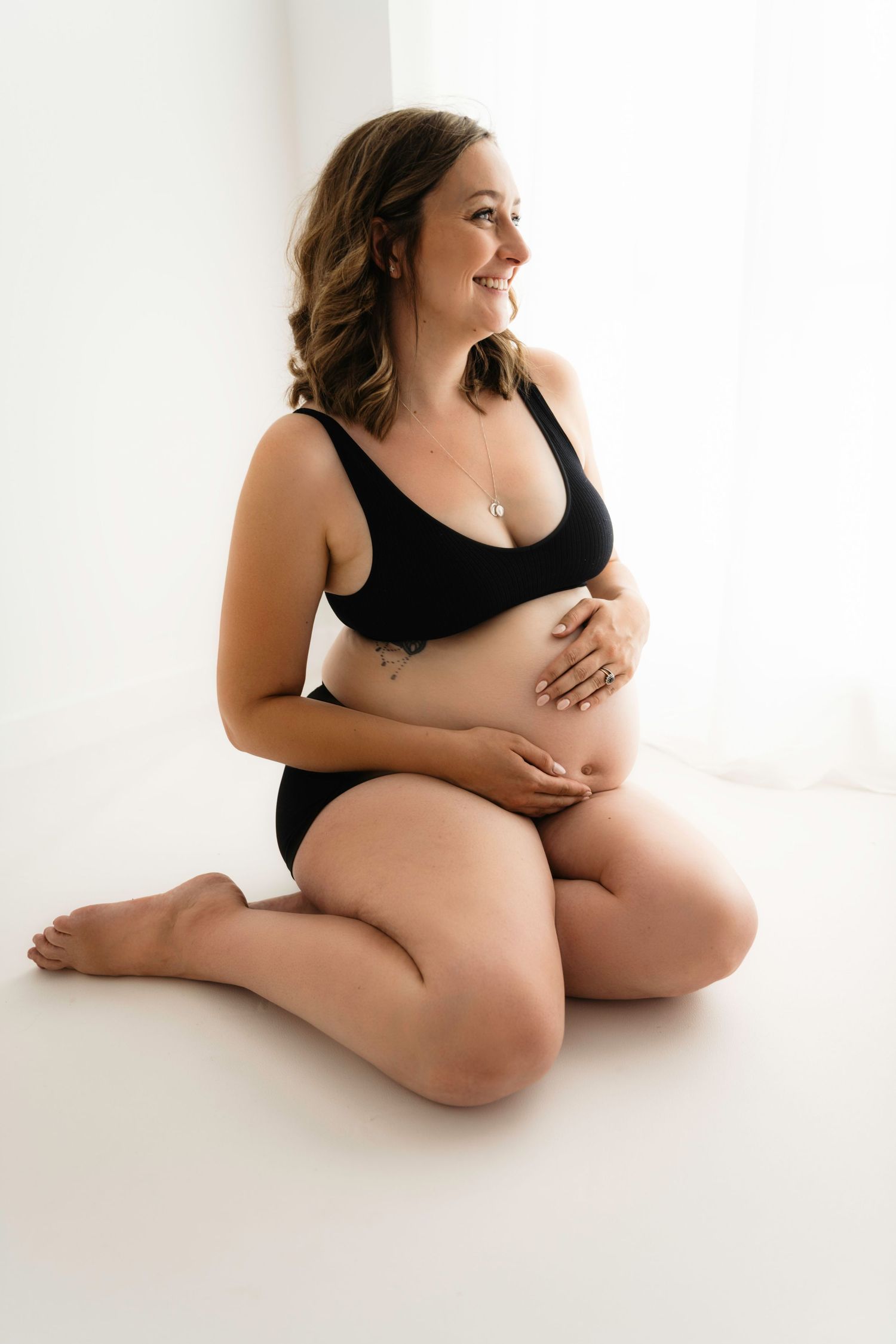 Artistic maternity poses showing pregnant woman sitting in black attire during a Maternity session in Corby, Northamptonshire