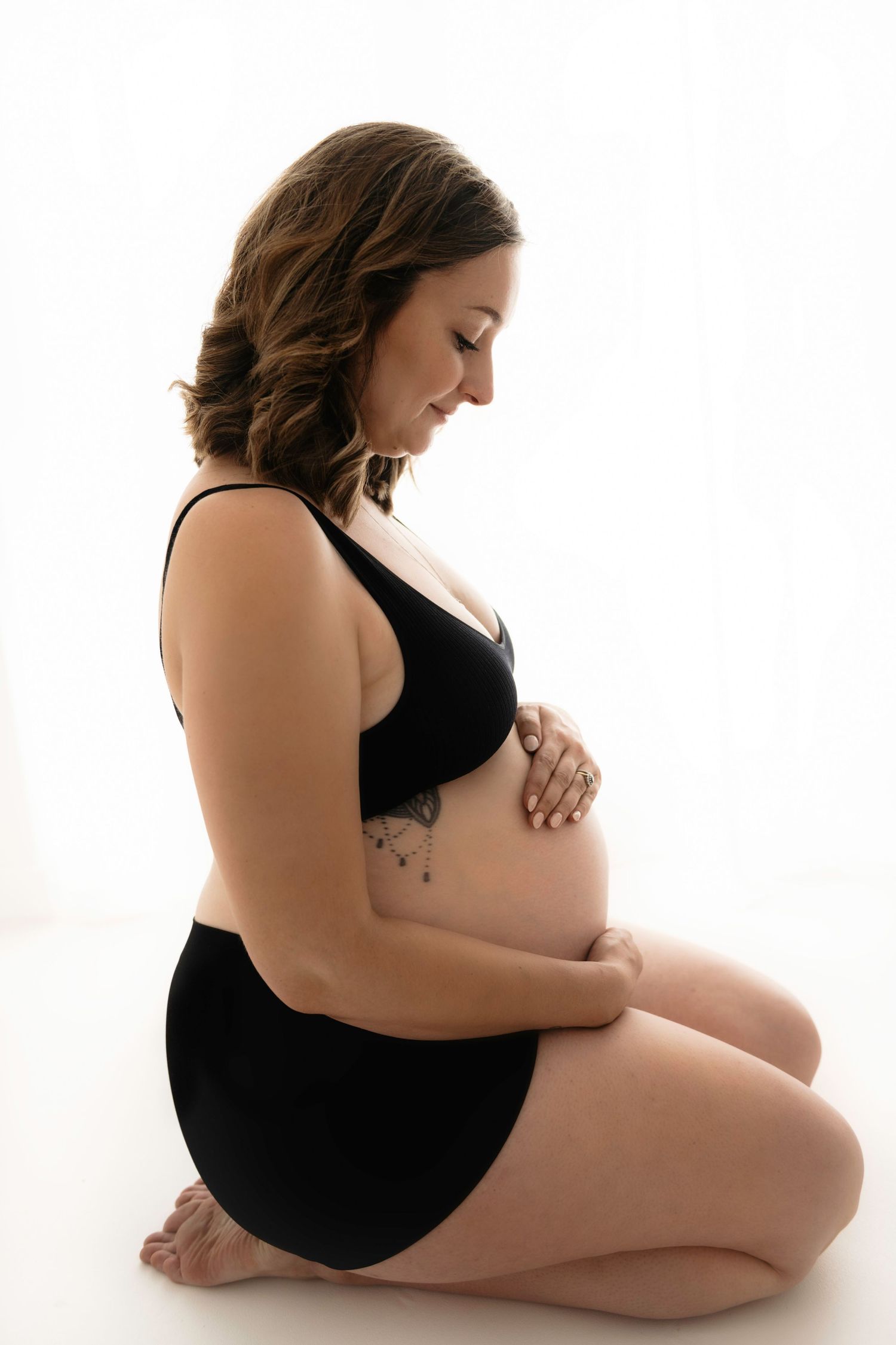 Artistic maternity poses showing pregnant woman in black against white background.