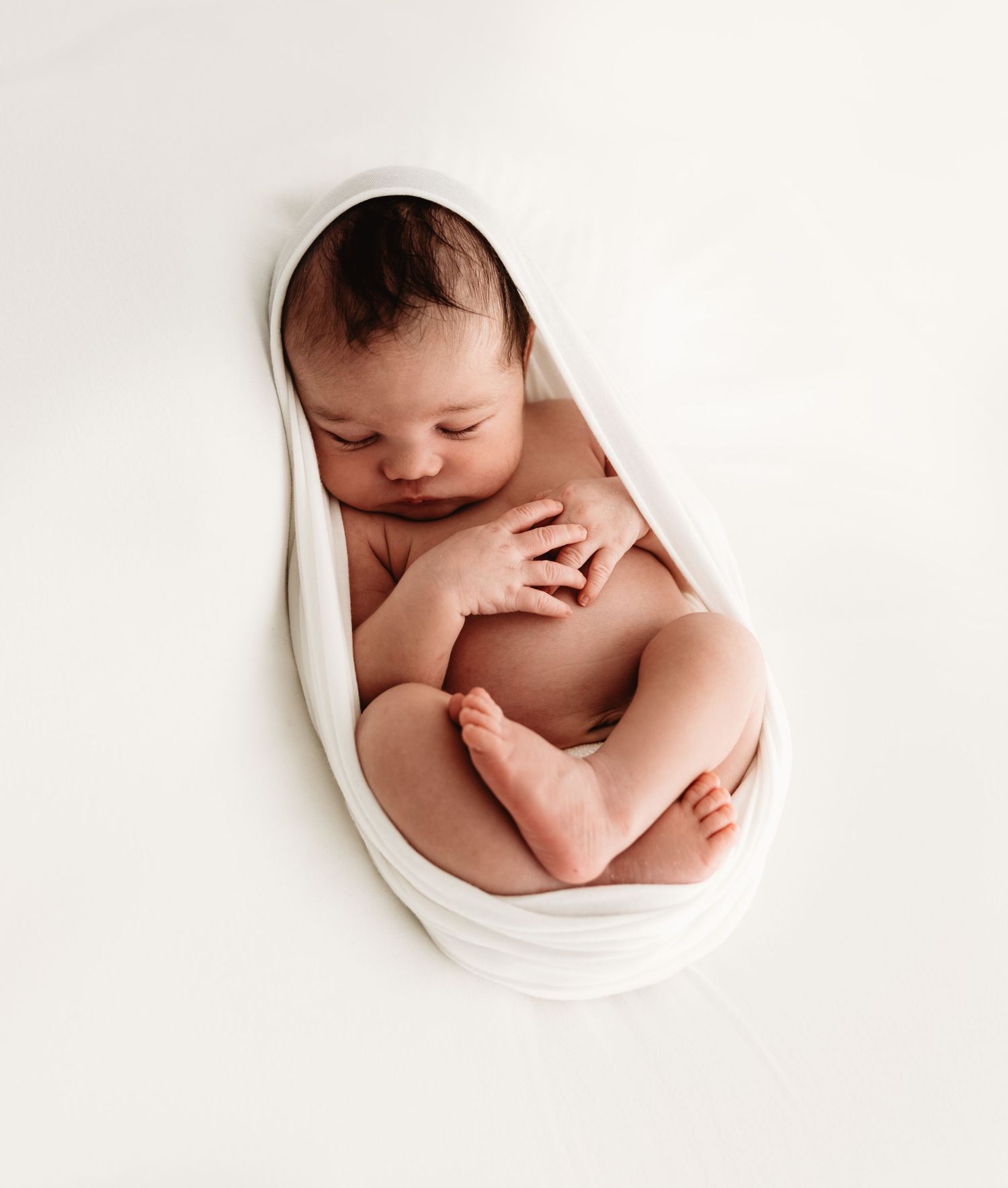 Artistic newborn photography series showing baby curled up in white circular frames against light background.