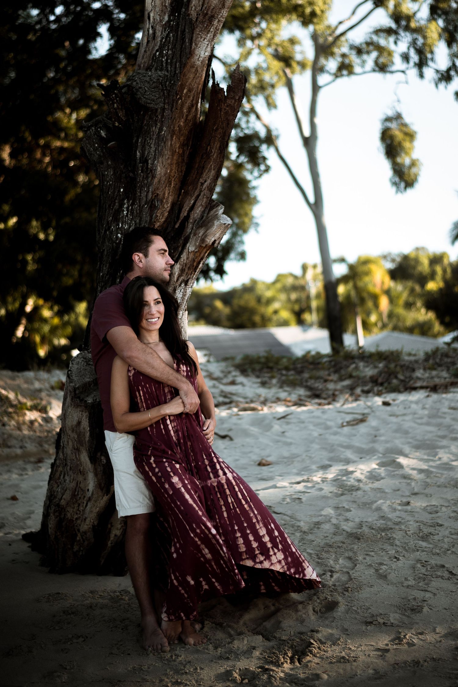 engaged couple leaning against tree at the beach in cairns © 2025 Jenna Hennessy / The Tone Curve