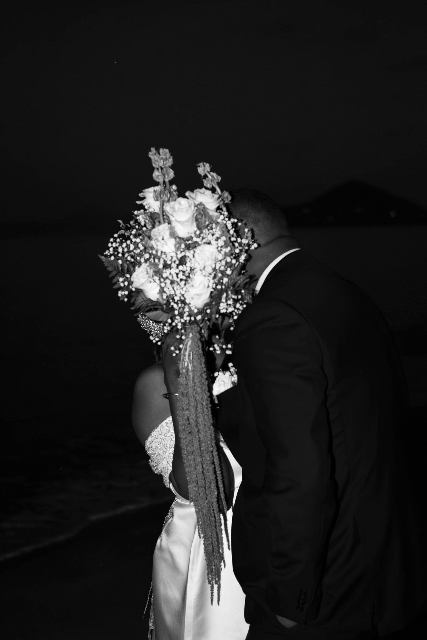Bride and Groom kissing on the beach, bouquet of flowers, elopement cairns