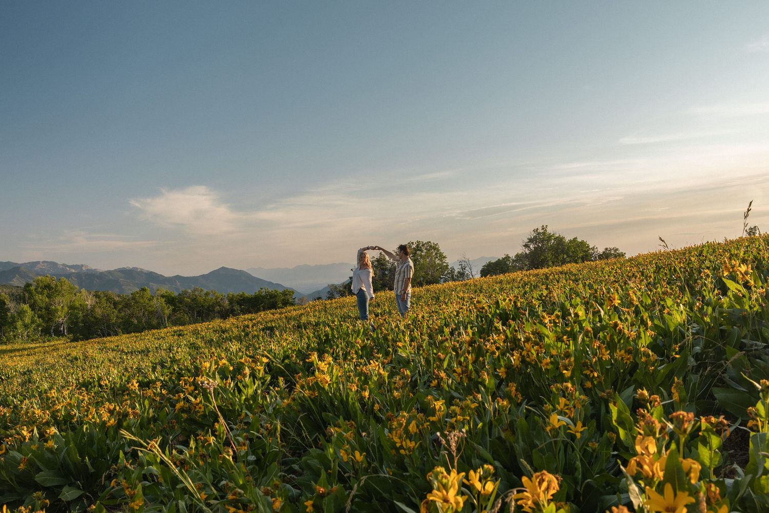 A couple dancing at sunset in a meadow full of wild flowers. Utah summer.
