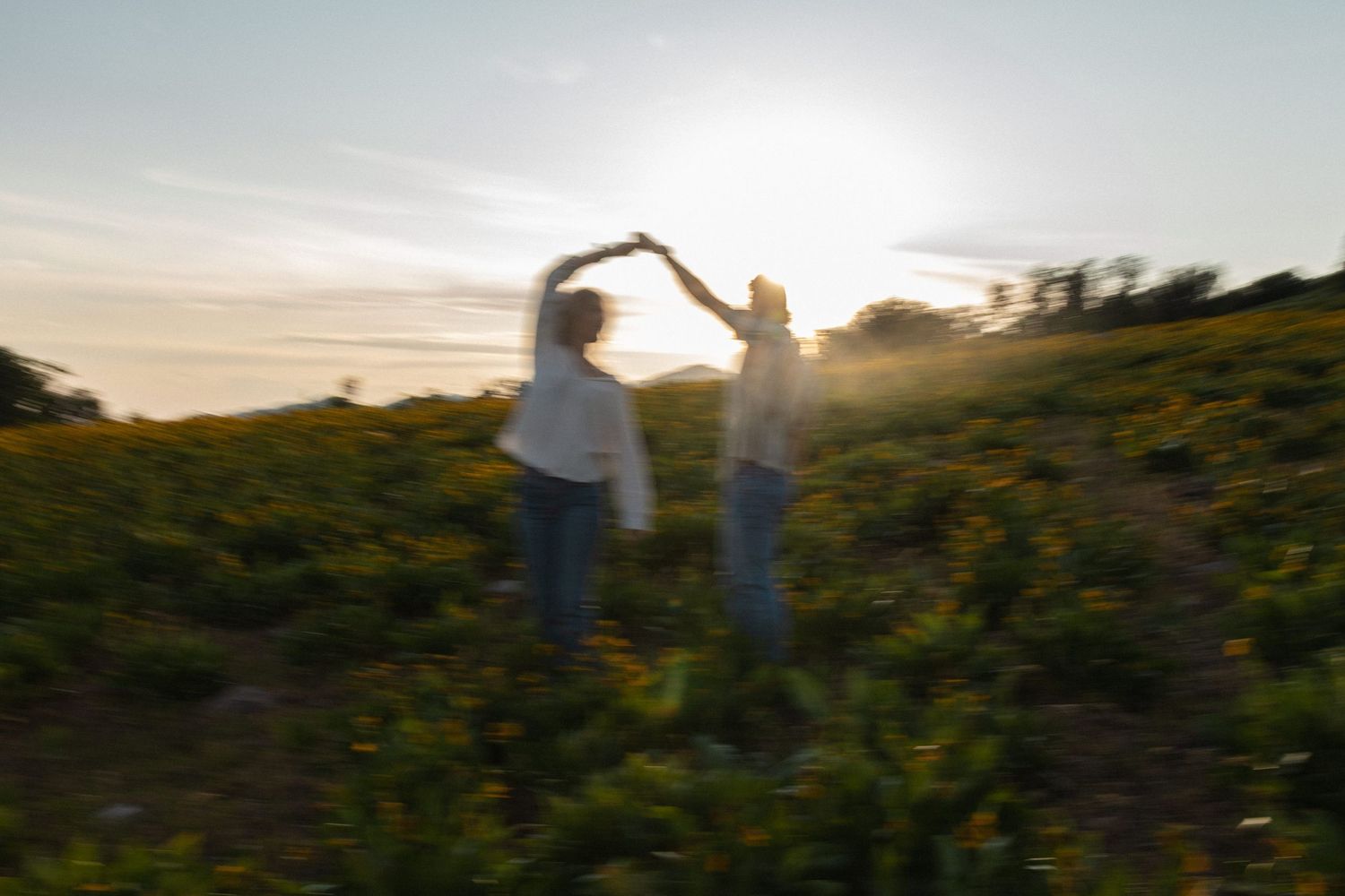 Blurry photo of a couple dancing at sunset in a field of wild flowers.