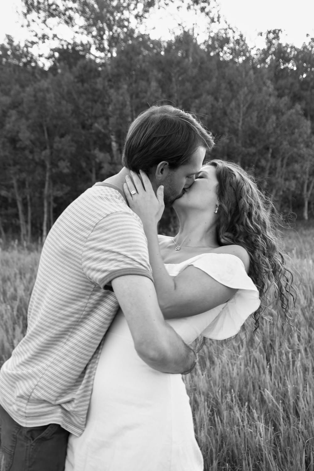 A black and white photo of a couple passionately kissing in the mountains at Snowbasin, Utah.