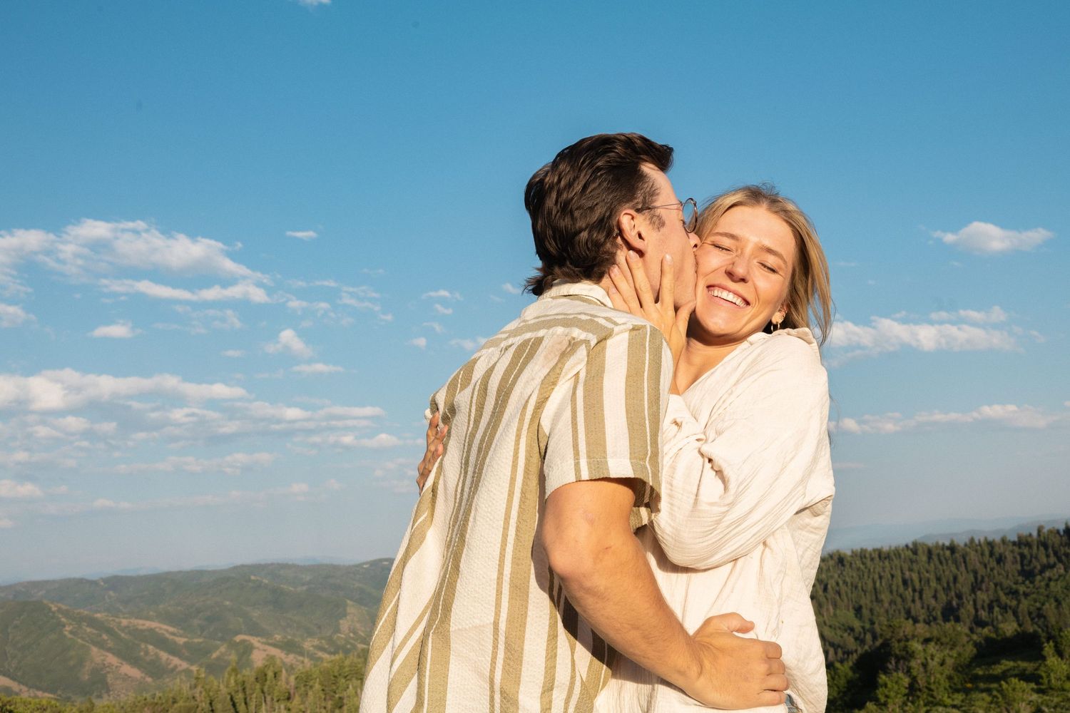 A couple glowing in the sun kissing on top of Black Mountain Pass.