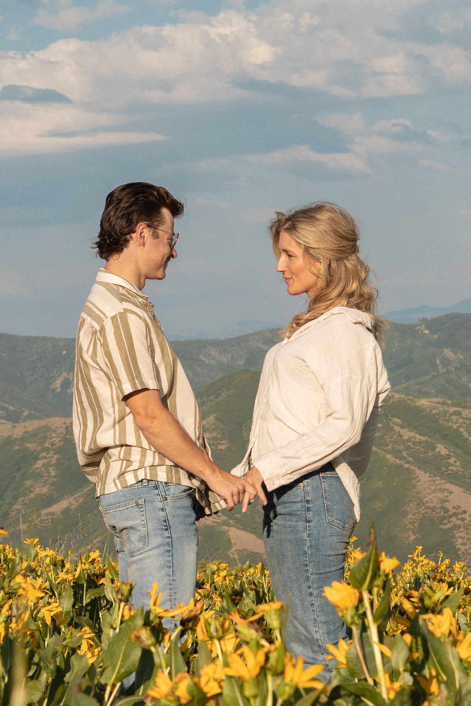 A couple holding hands standing in the field of wild flowers.