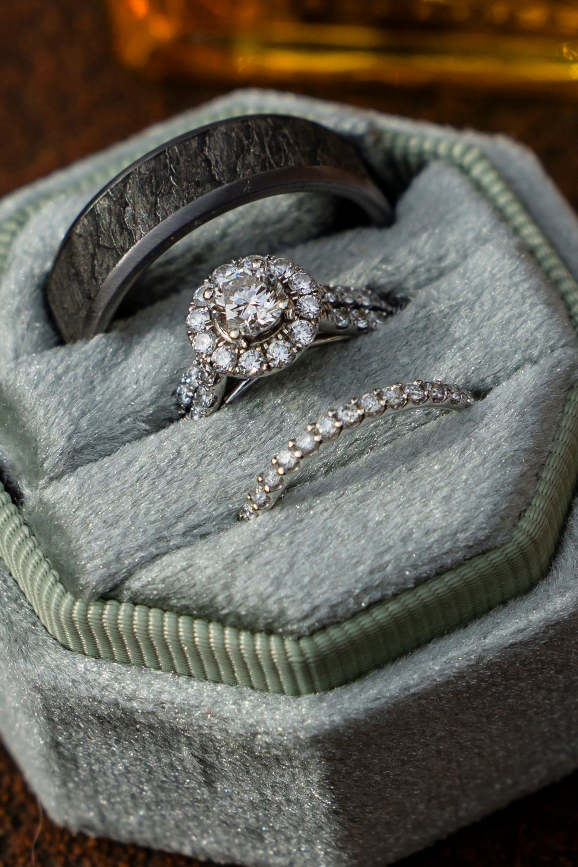 Close-up macro shots of a sparkling diamond engagement ring displayed on a gray textured surface in warm lighting.
