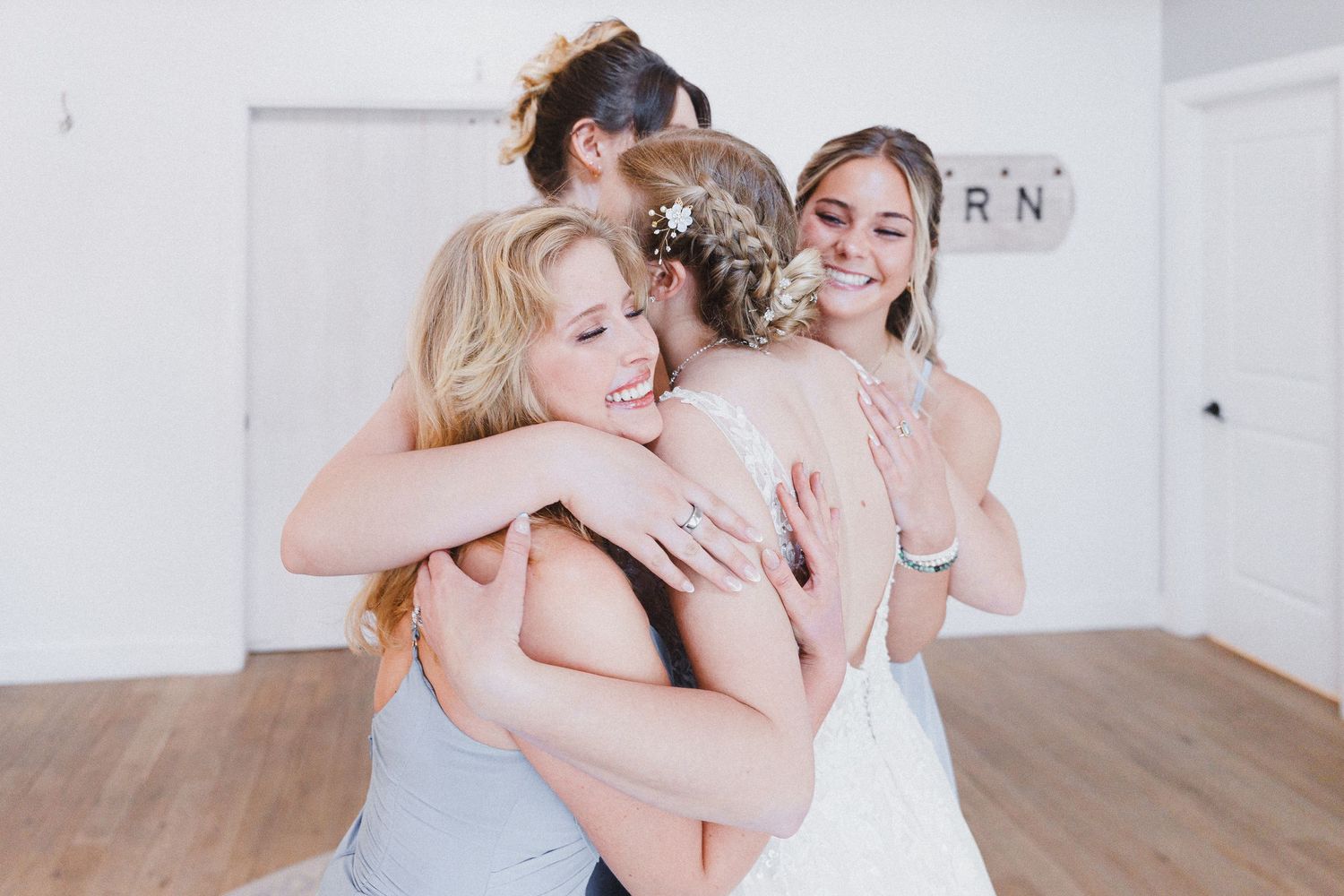 A pair of individuals hug warmly in a minimalist white studio space with natural lighting.
