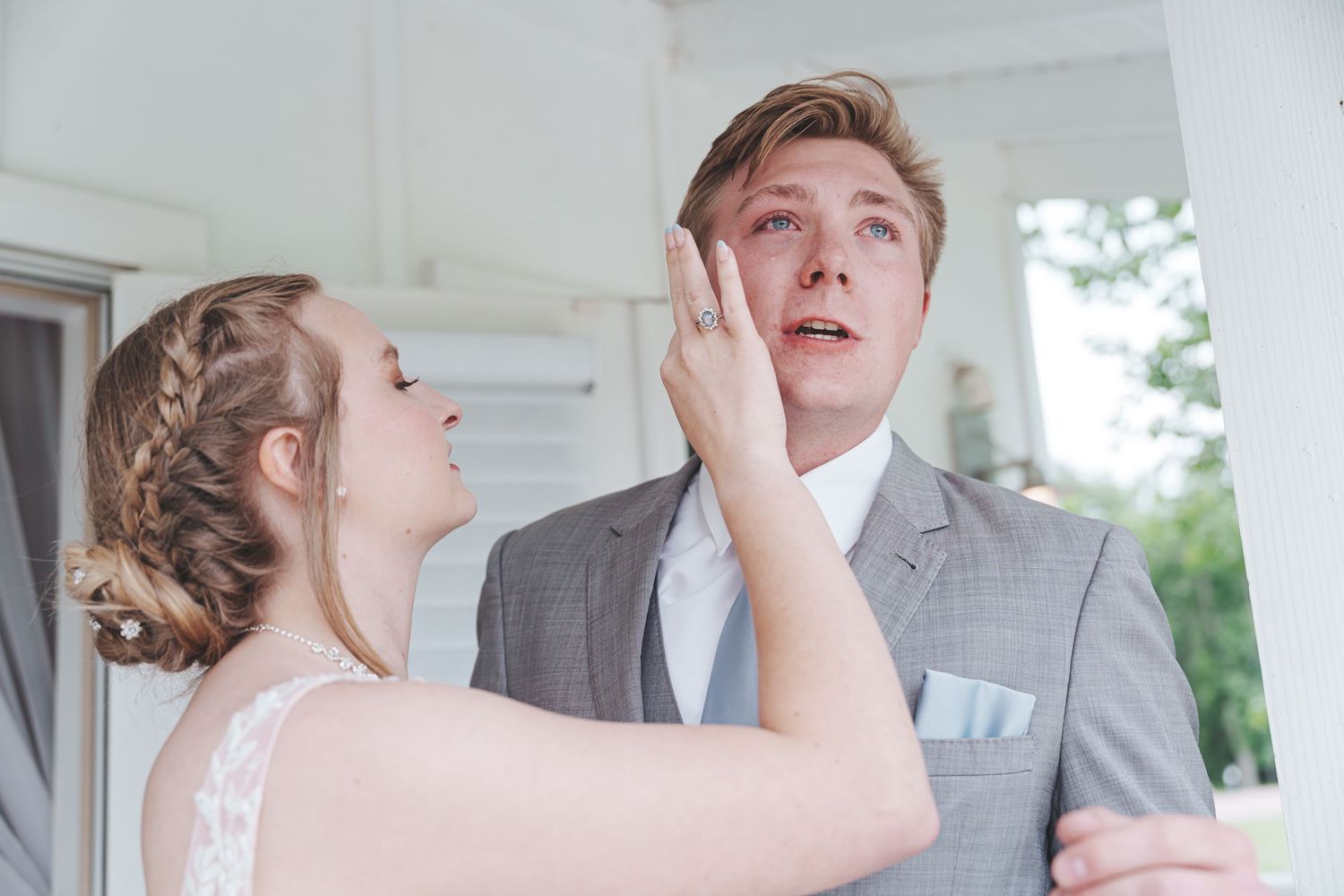 A couple shares a playful moment on their wedding day in light formal attire.