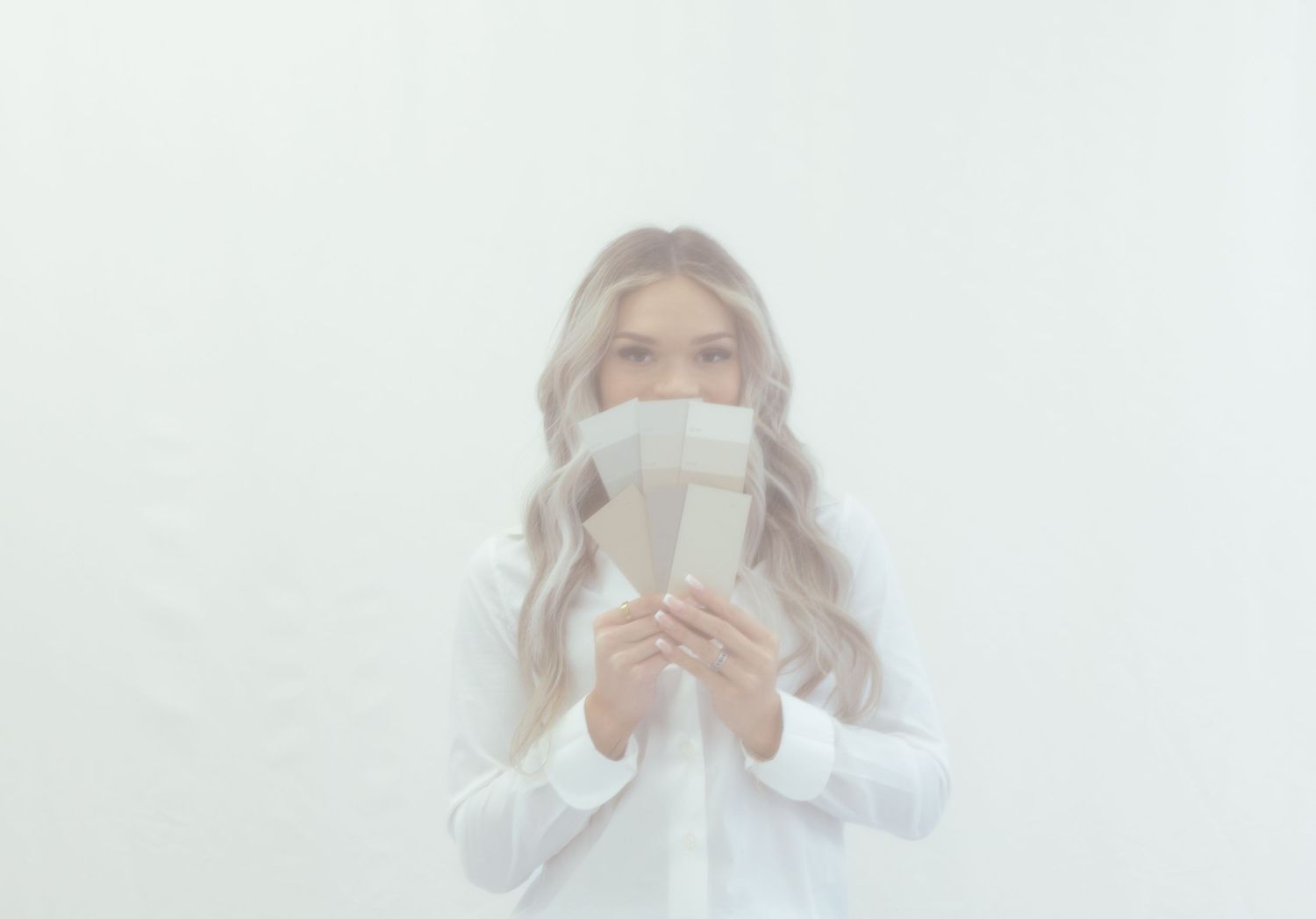 A dreamy portrait of someone holding a coffee cup against a bright white background.