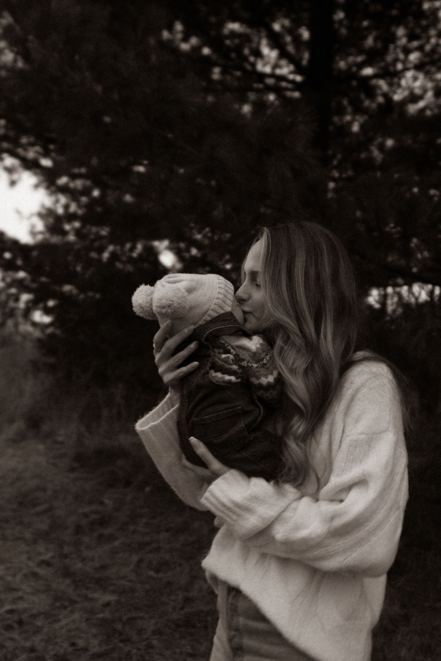 Tender moment with baby bundled in winter wear captured in black and white.