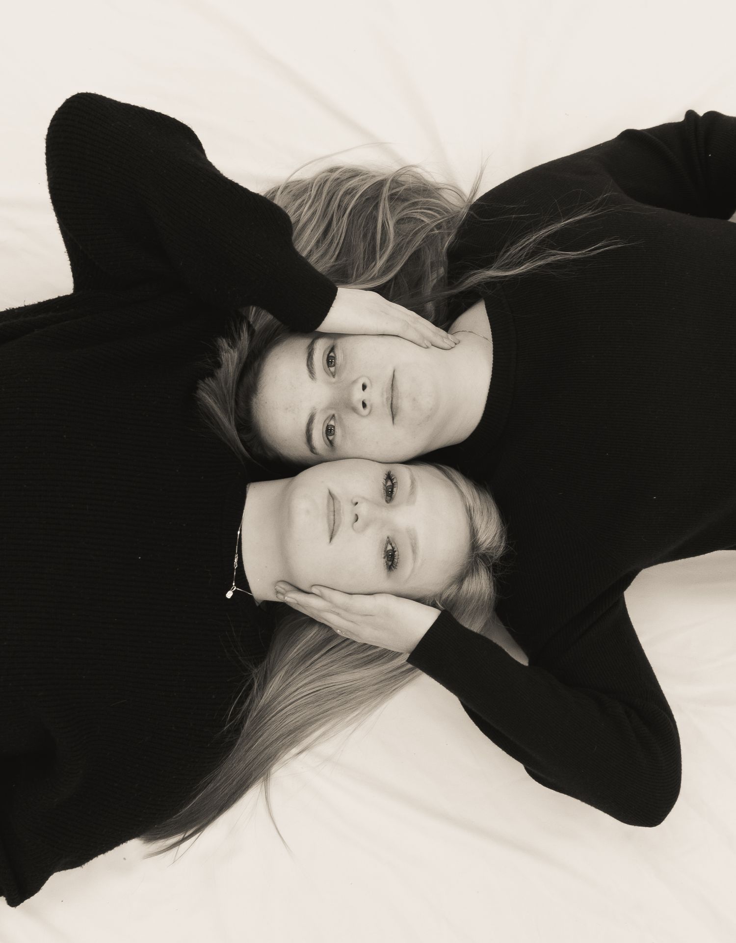 Artistic black and white portrait of two people lying down in opposite directions.