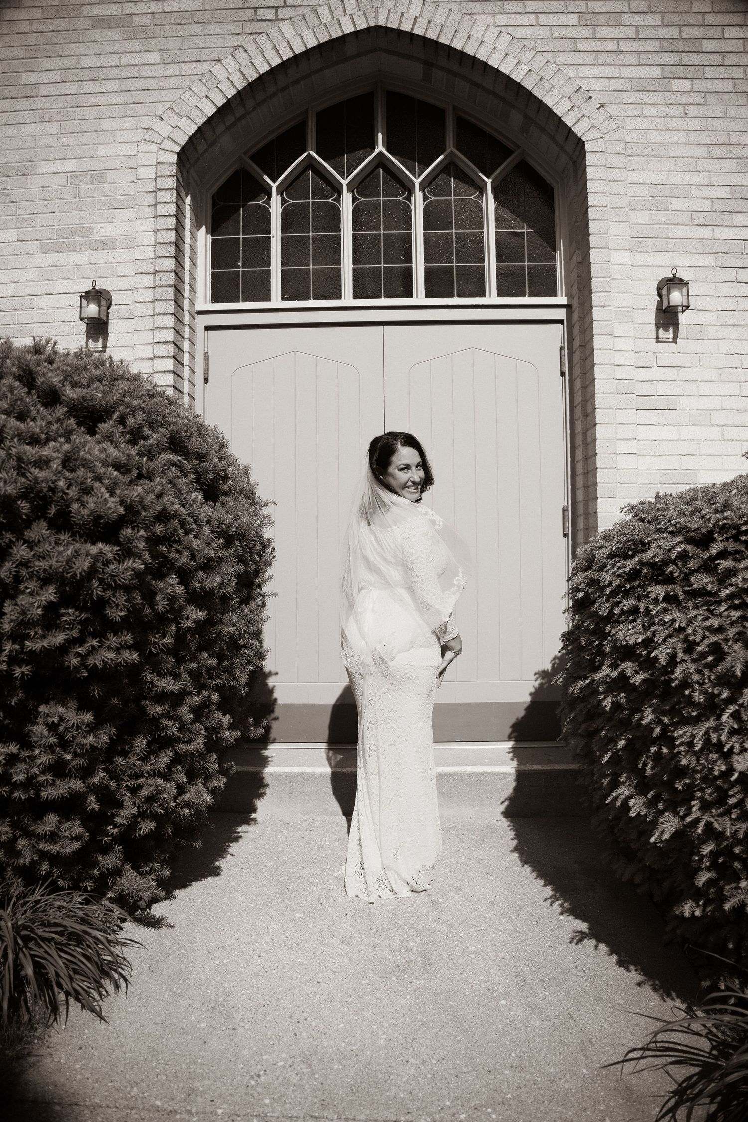 A figure in a white dress stands in front of a brick archway, shown in a series of black and white film photographs.