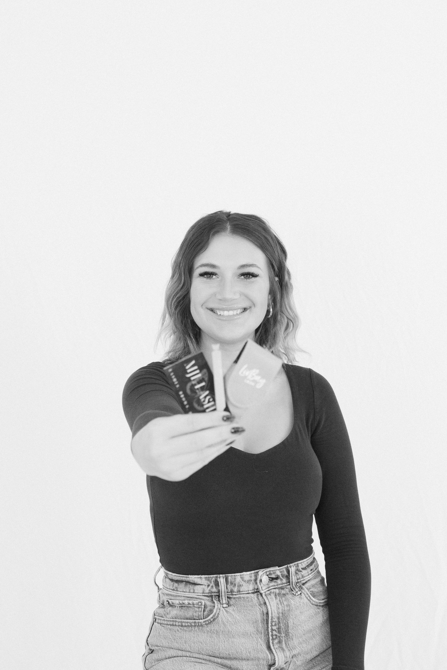 Woman in black top holding object against white background.