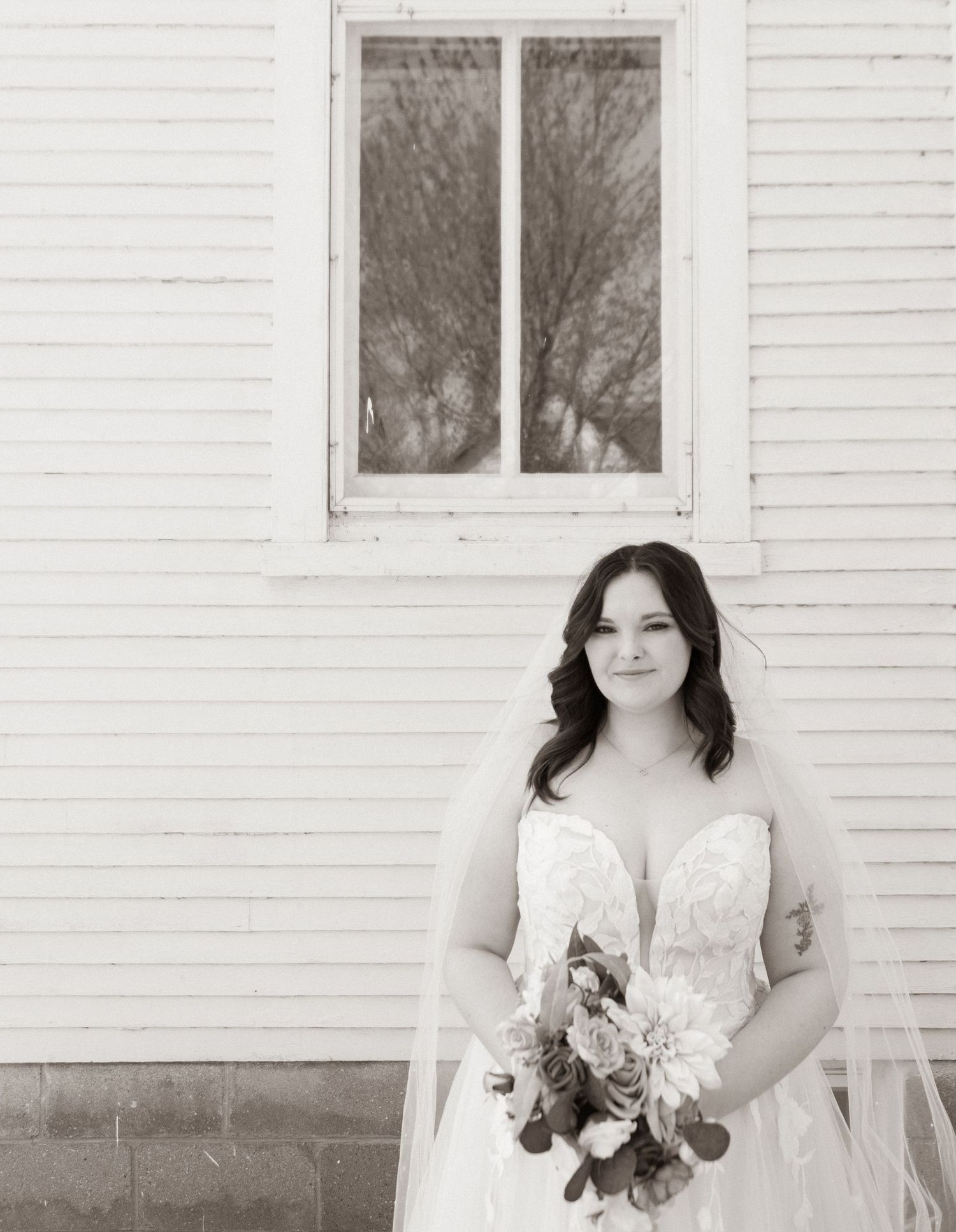 A classic black and white bridal portrait against white siding and window.