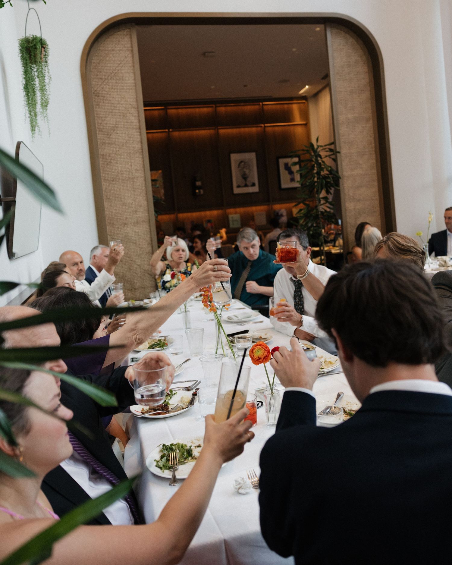 Group of people raising and toasting wine glasses during an indoor celebration at a formal restaurant.