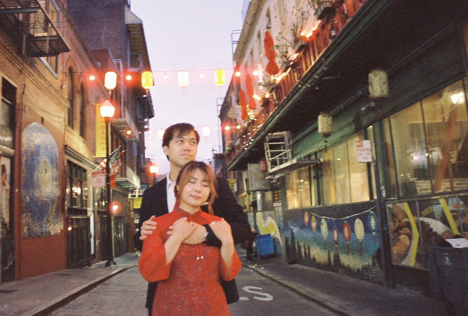 A colorful lantern-lit alley in an Asian night market with red glowing lights illuminating the narrow street.