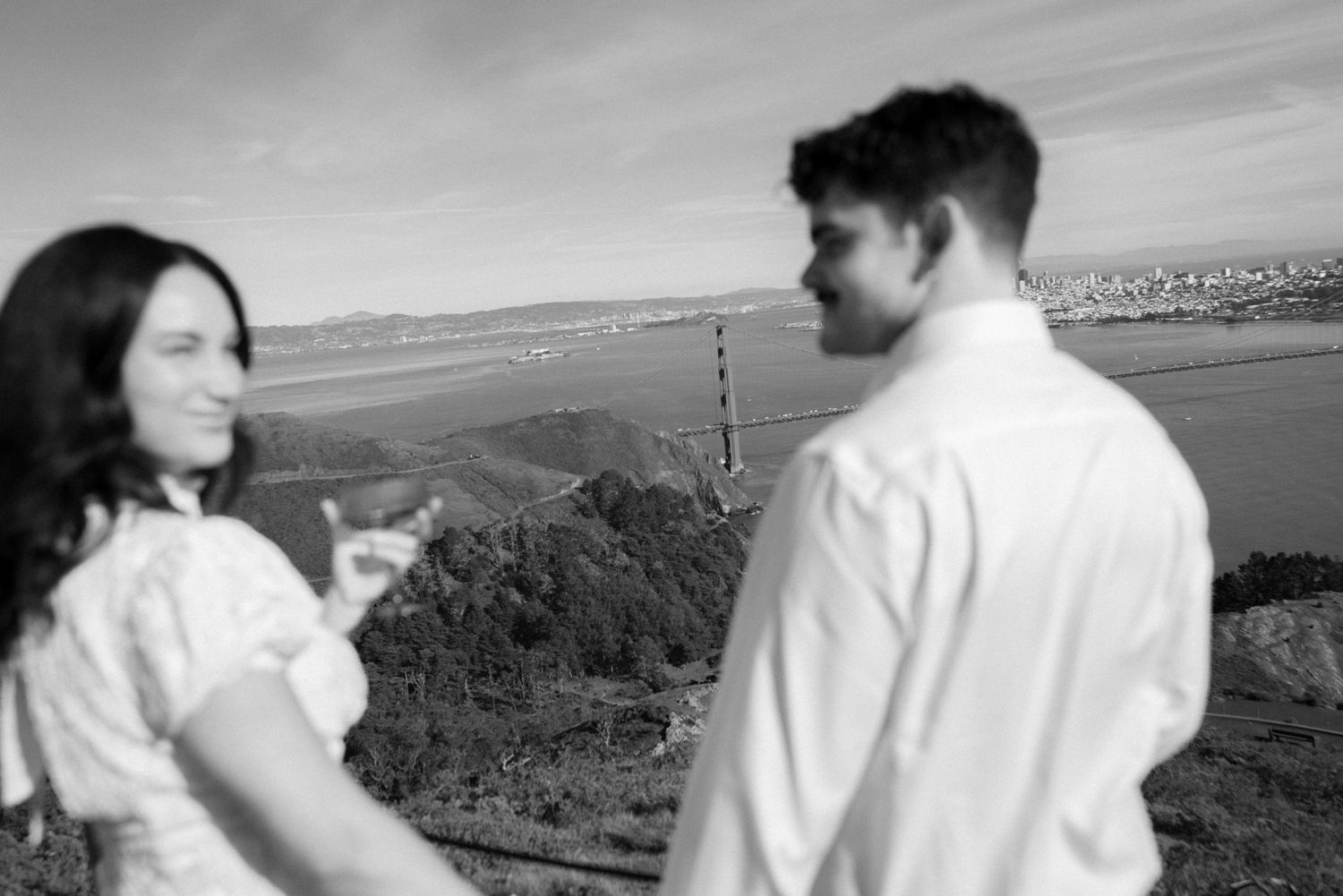 A sequence of monochrome photos shows two people in white shirts embracing against a scenic outdoor landscape.